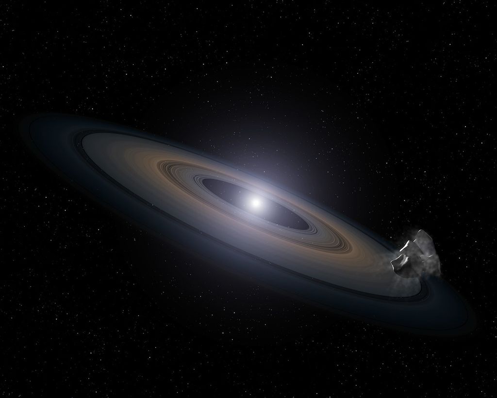 A glowing white star sits at the center of a disk of debris composed of numerous rings, very much resembling the rings of Saturn. They're light orange near the center, fading to lavender, fading to deep blue at the edges, with several gaps. In the foreground on the right is a rocky gray asteroid.