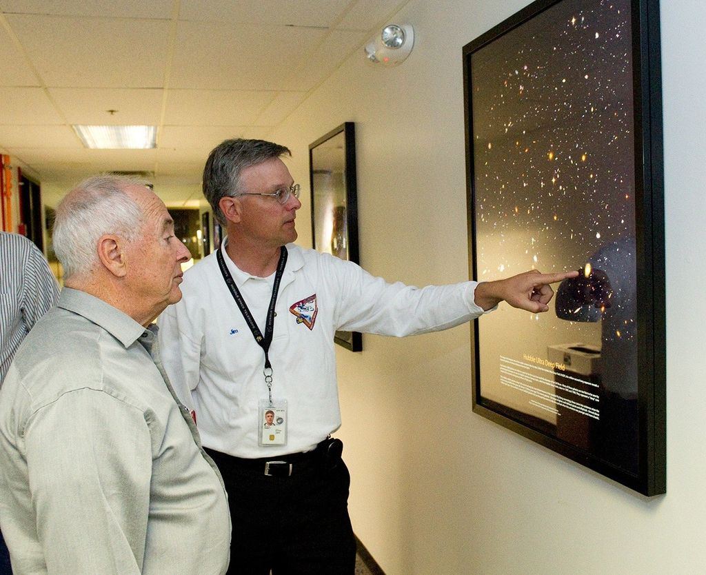 Jim Jeletic, center, points to a framed picture of the Hubble Ultra Deep Field while explaining it to Bill Anders, left.