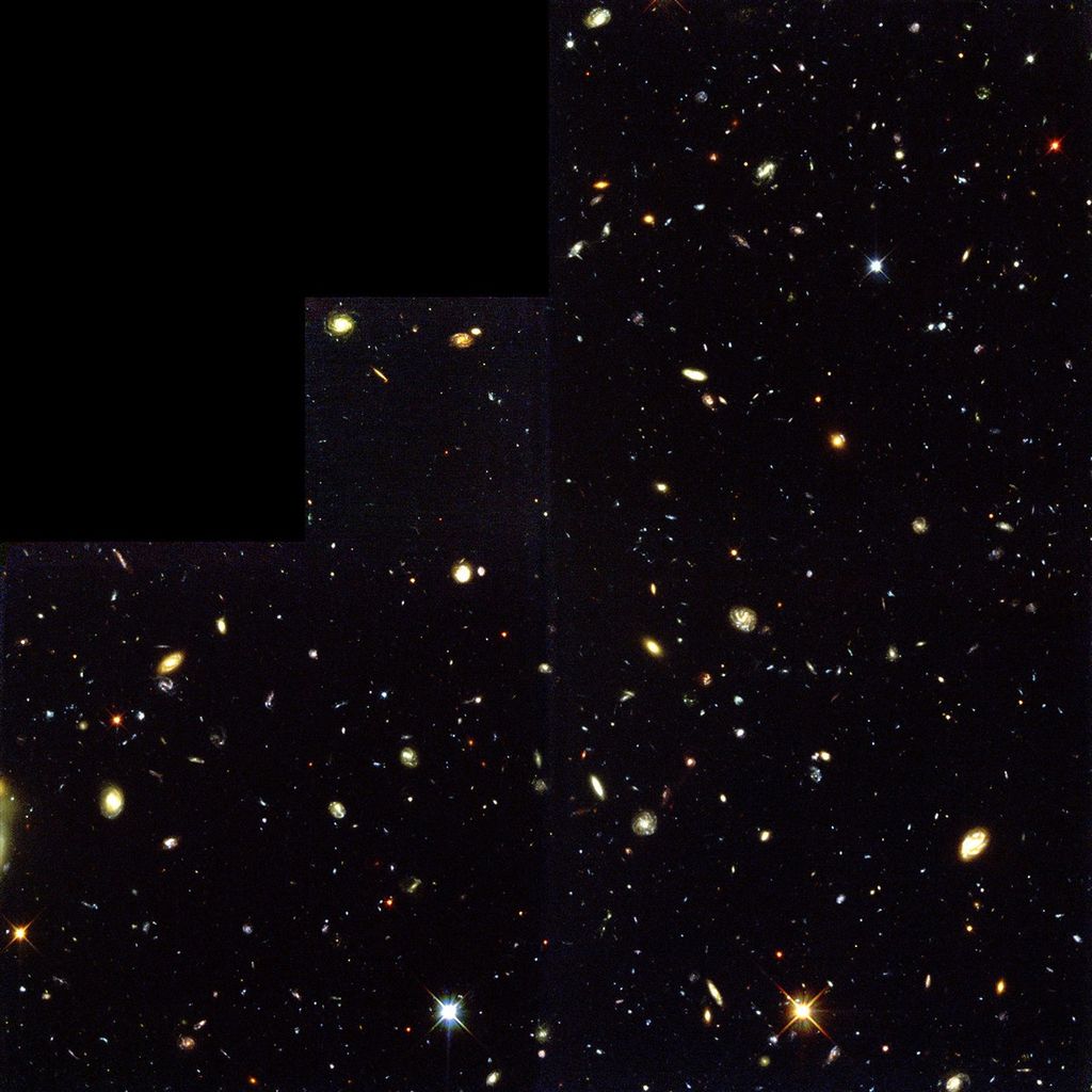 Thousands of galaxies of many shapes and colors float in a small section of the black background of space.
