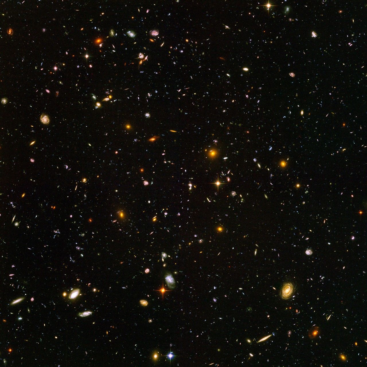 Field is filled with galaxies in colors of white, yellow, blue-white, and red; all on a black background.