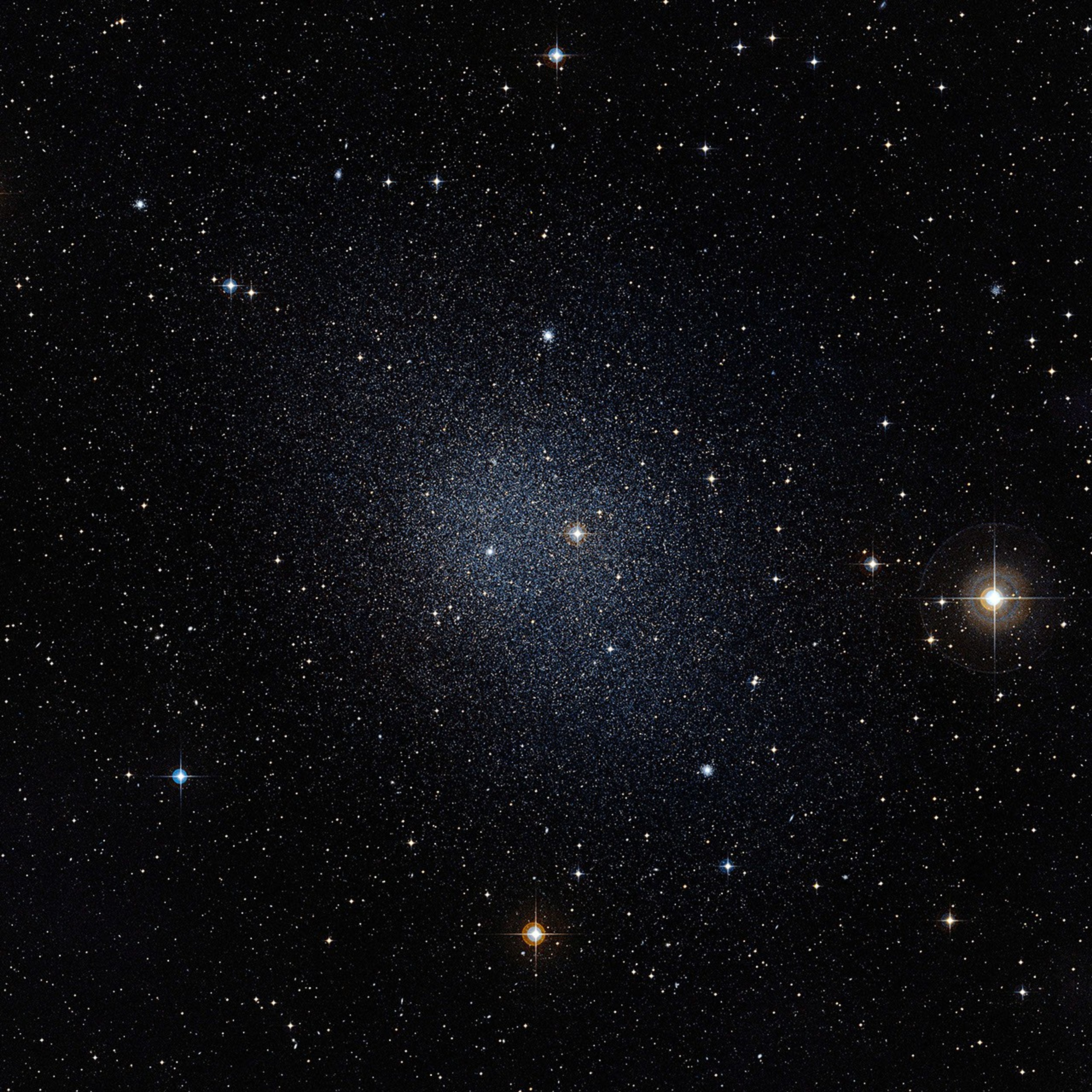 Against a black backdrop speckled with distant stars (and a few that are closer). The galaxy appears as a denser, fuzzy collection of stars near the center.