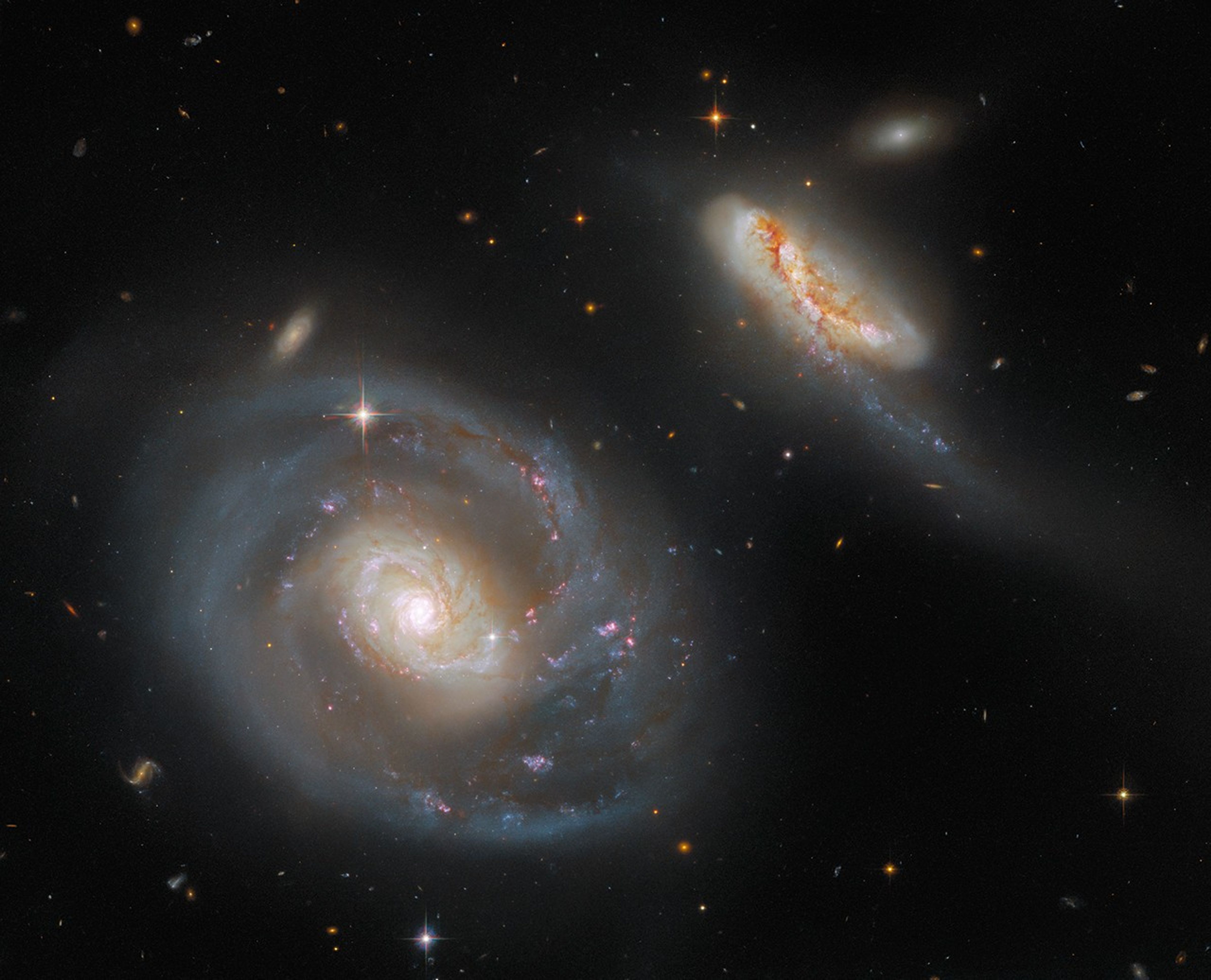 Large face-on spiral galaxy on the lower-left half of the image with a smaller galaxy in the upper left. Several smaller galaxies are seen in the background.