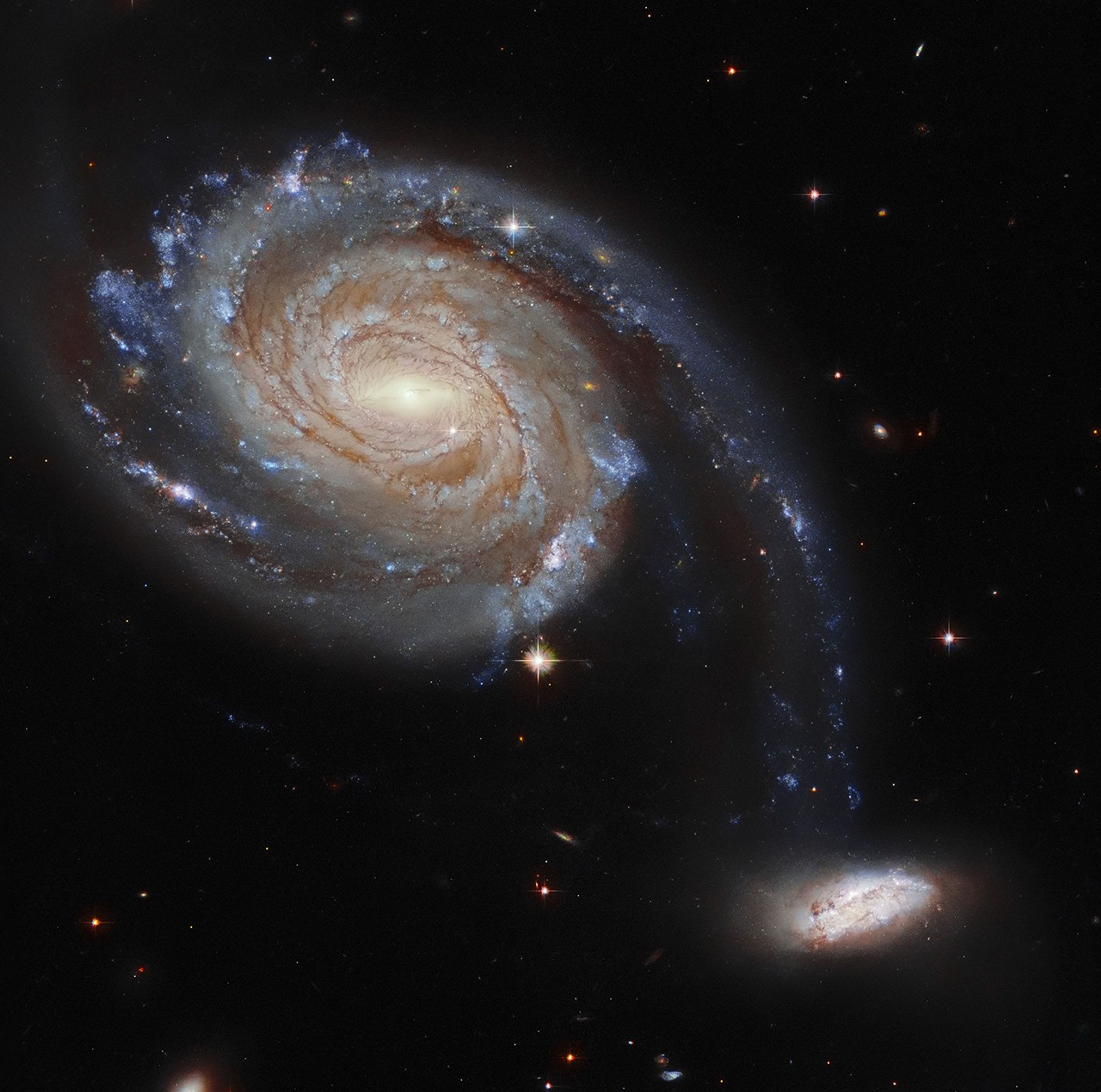 Two spiral galaxies, one at upper-left the other at lower-right, both are nearly face-on, providing views of stars, gas, and dust. Background stars and galaxies.