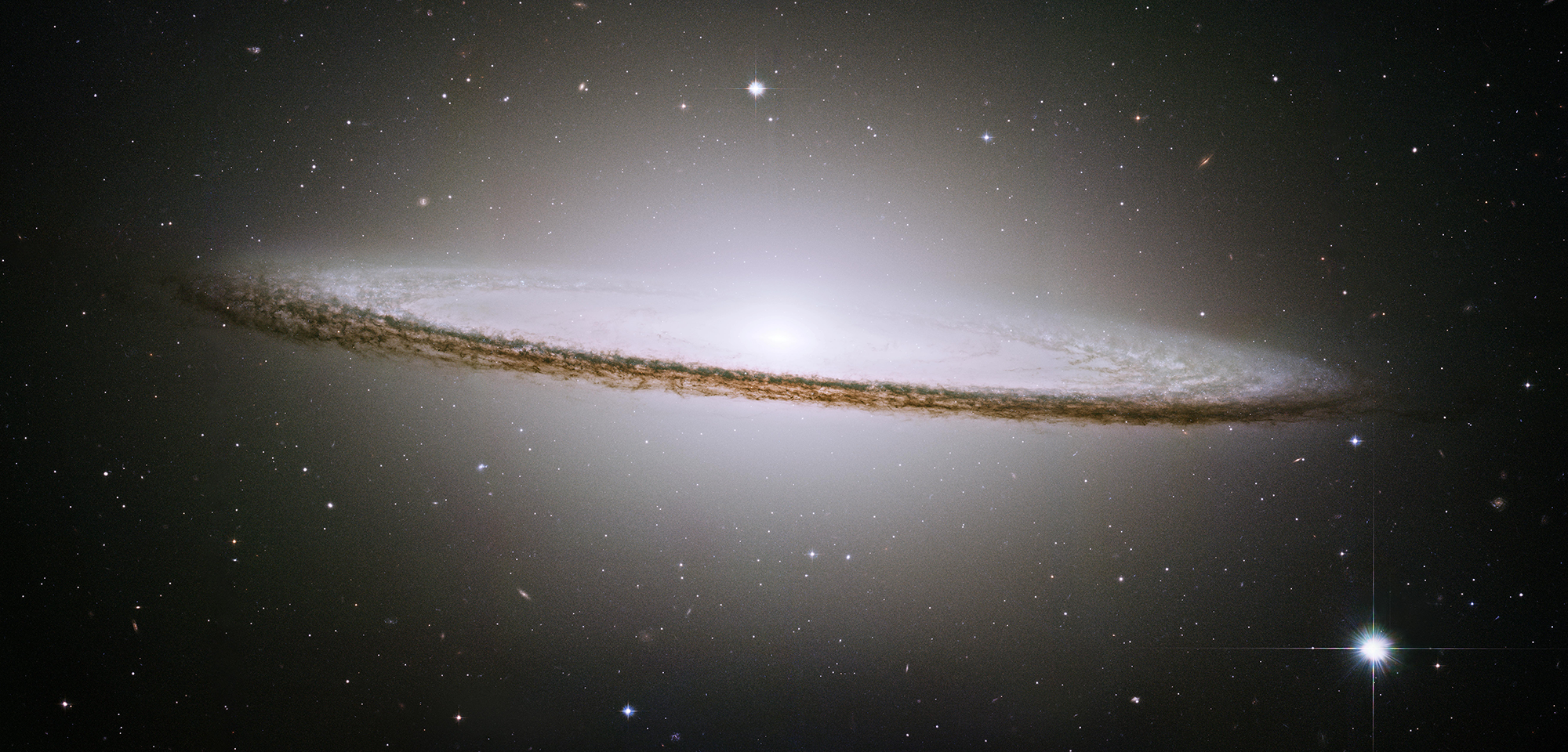 A very oblong, pale white disk with a bright center extends from left to right on a black background.