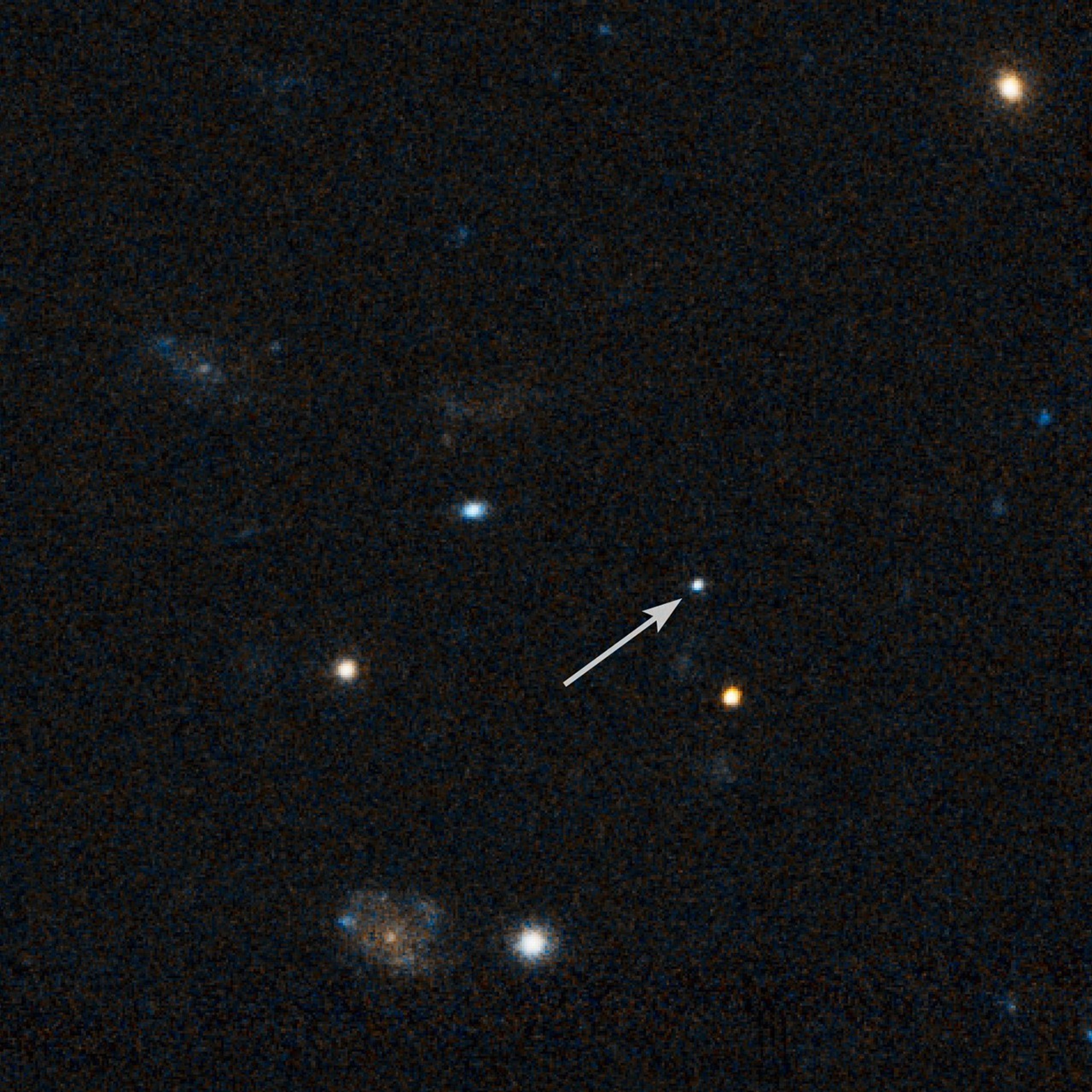 Black background with a few galaxies and several bright spots. One bright-white dot has an arrow pointing to it.