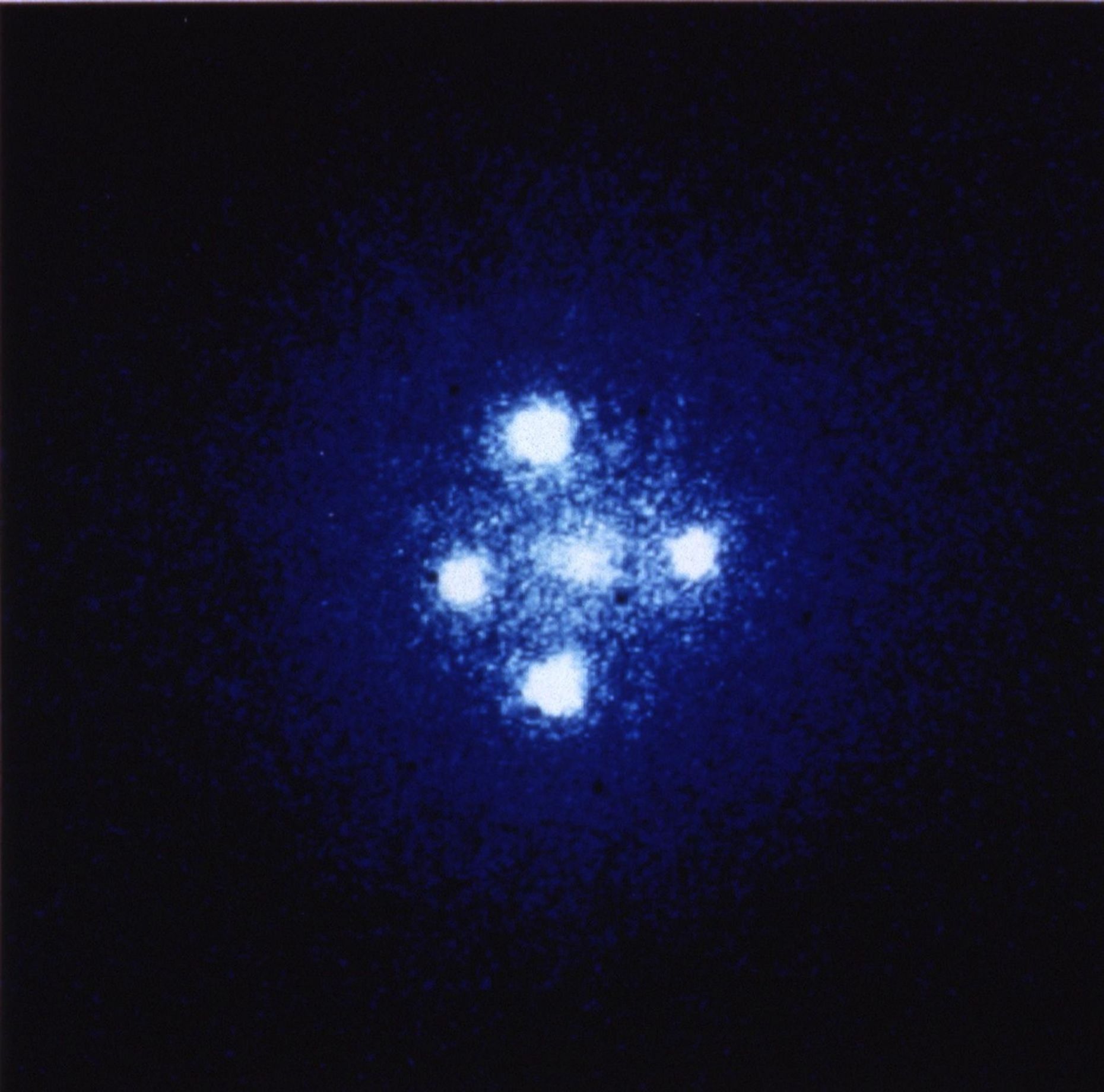 Four bright-white circles, positioned in the shape of a cross around a fifth more muted white spot in the center.