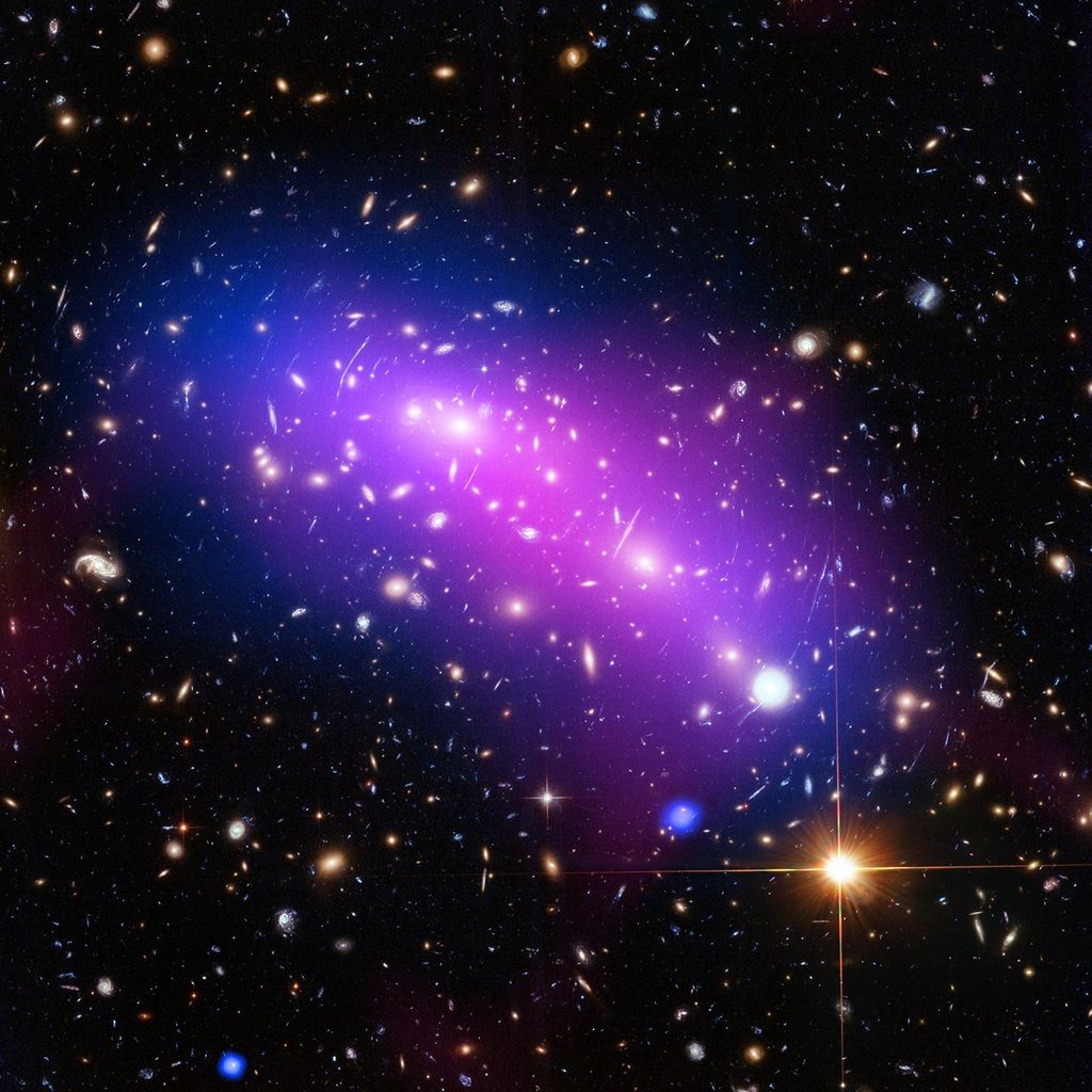A black background is dotted with galaxies and a few foreground stars. Blobs of purple, blue, and reddish-purple denote temperature of matter.