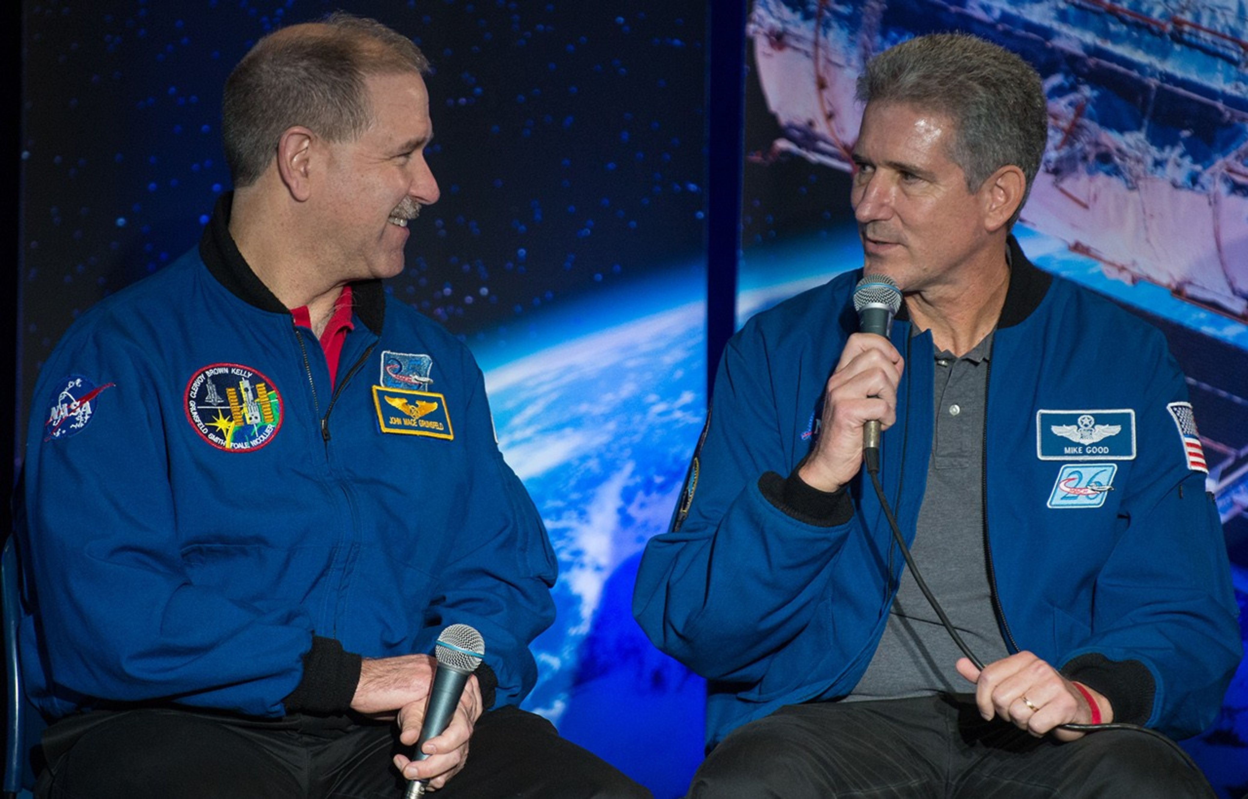 Michael Good, right, addresses the audience while exchanging smiles with fellow astronaut John Grunsfeld, left.