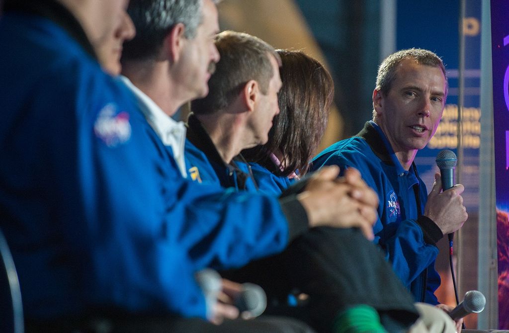 Drew Feustel, sitting farthest to the right at the far end of the panel, looks toward the camera and his fellow astronauts while the rest of the panel faced away from the camera toward him.