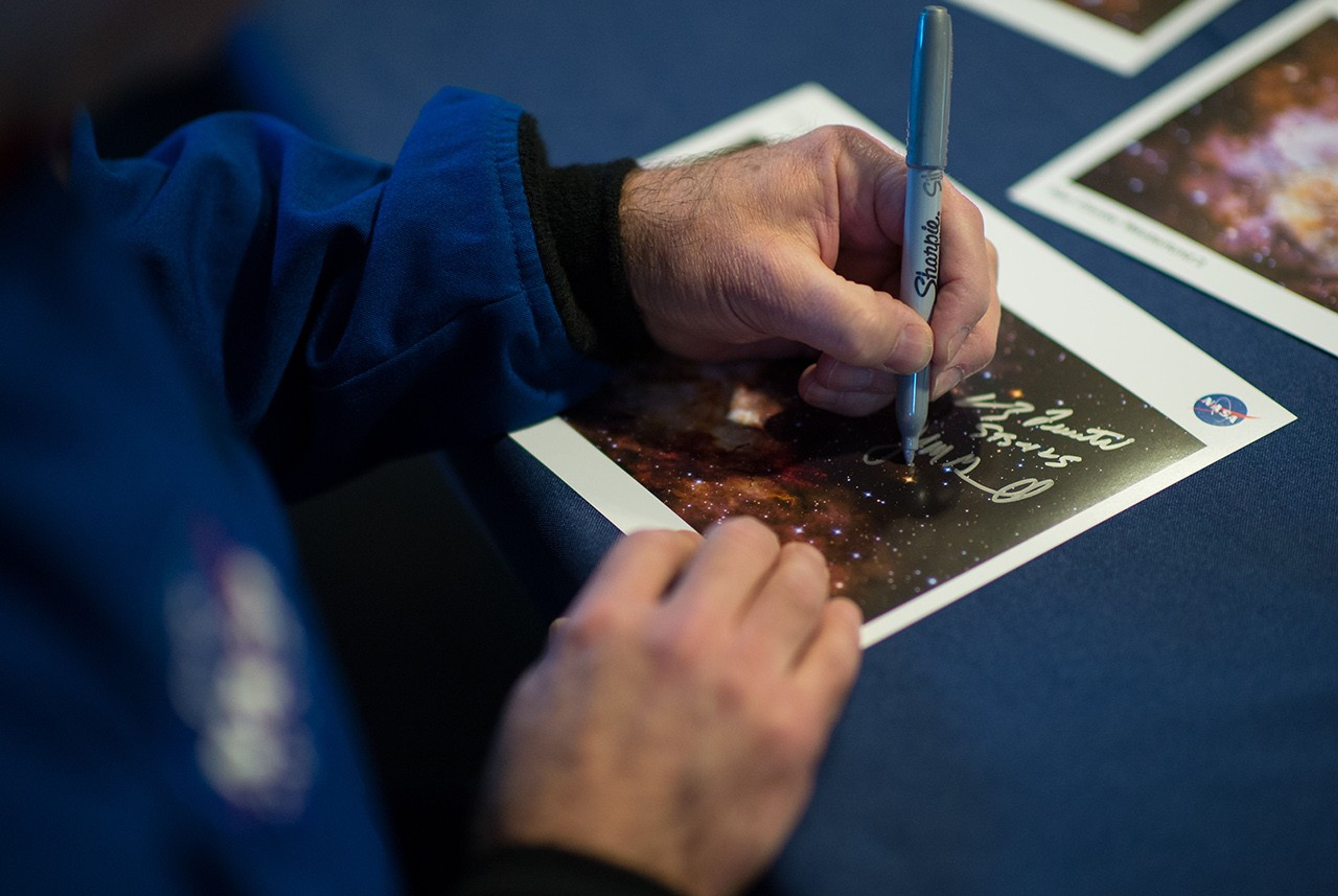 A photo of John Grunsfeld's hands as he signs a Hubble image of Westerlund 2 for a visitor.