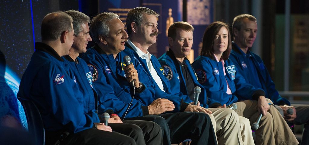 Astronaut Mike Massimino, third from the left, speaks to the audience while the other six astronauts listen.