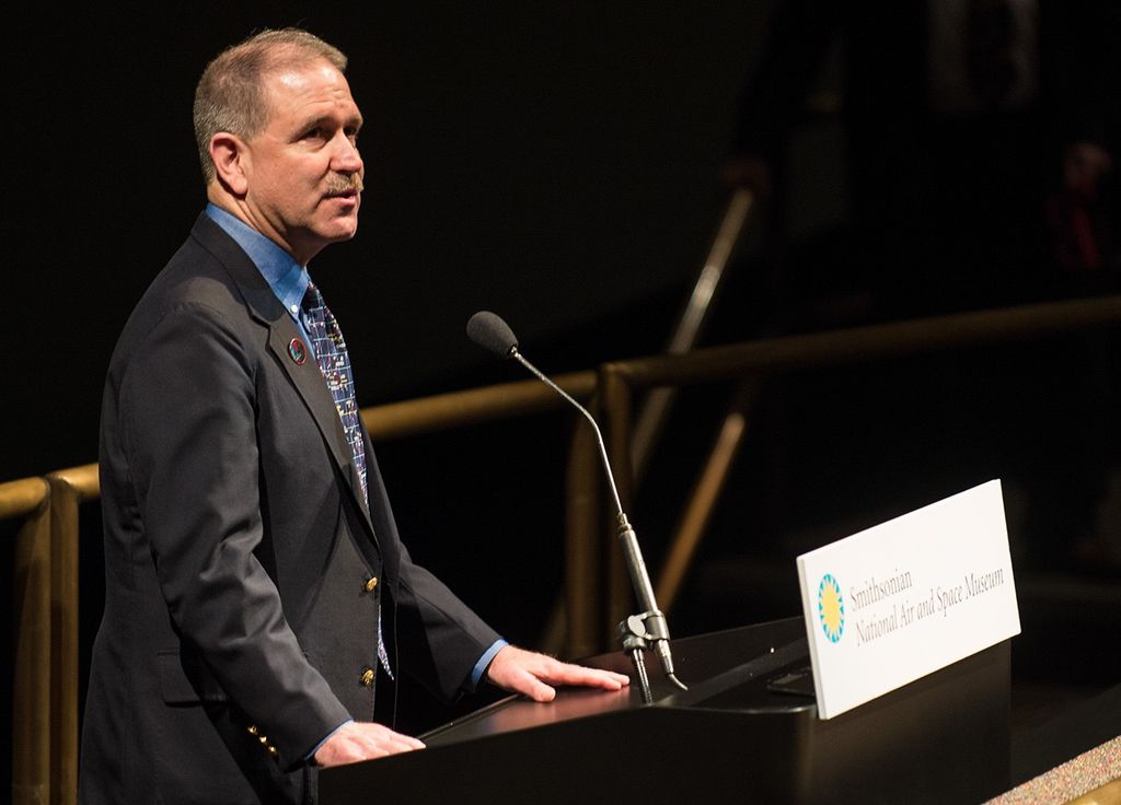 John Grunsfeld stands at the podium to address the audience.