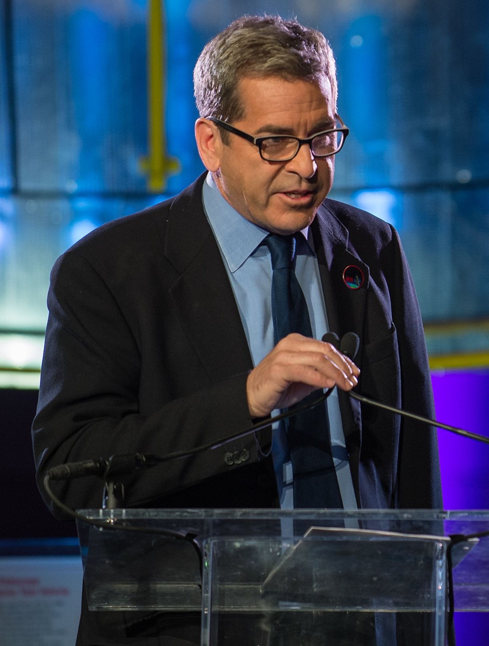 Miles O'Brien stands at the podium, addressing the audience.