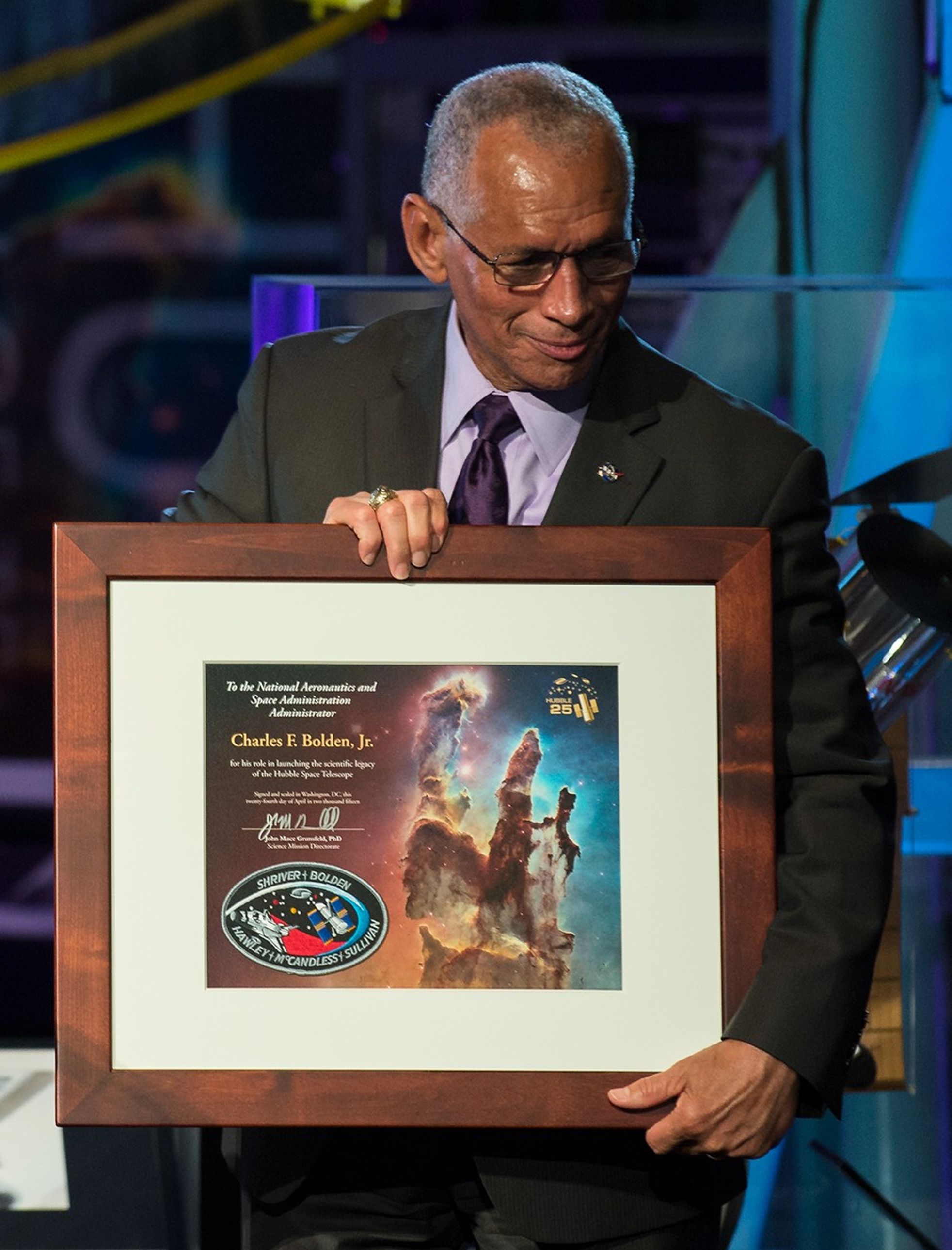 An overjoyed Charlie Bolden holds the framed Hubble anniversary plaque that was presented to him.