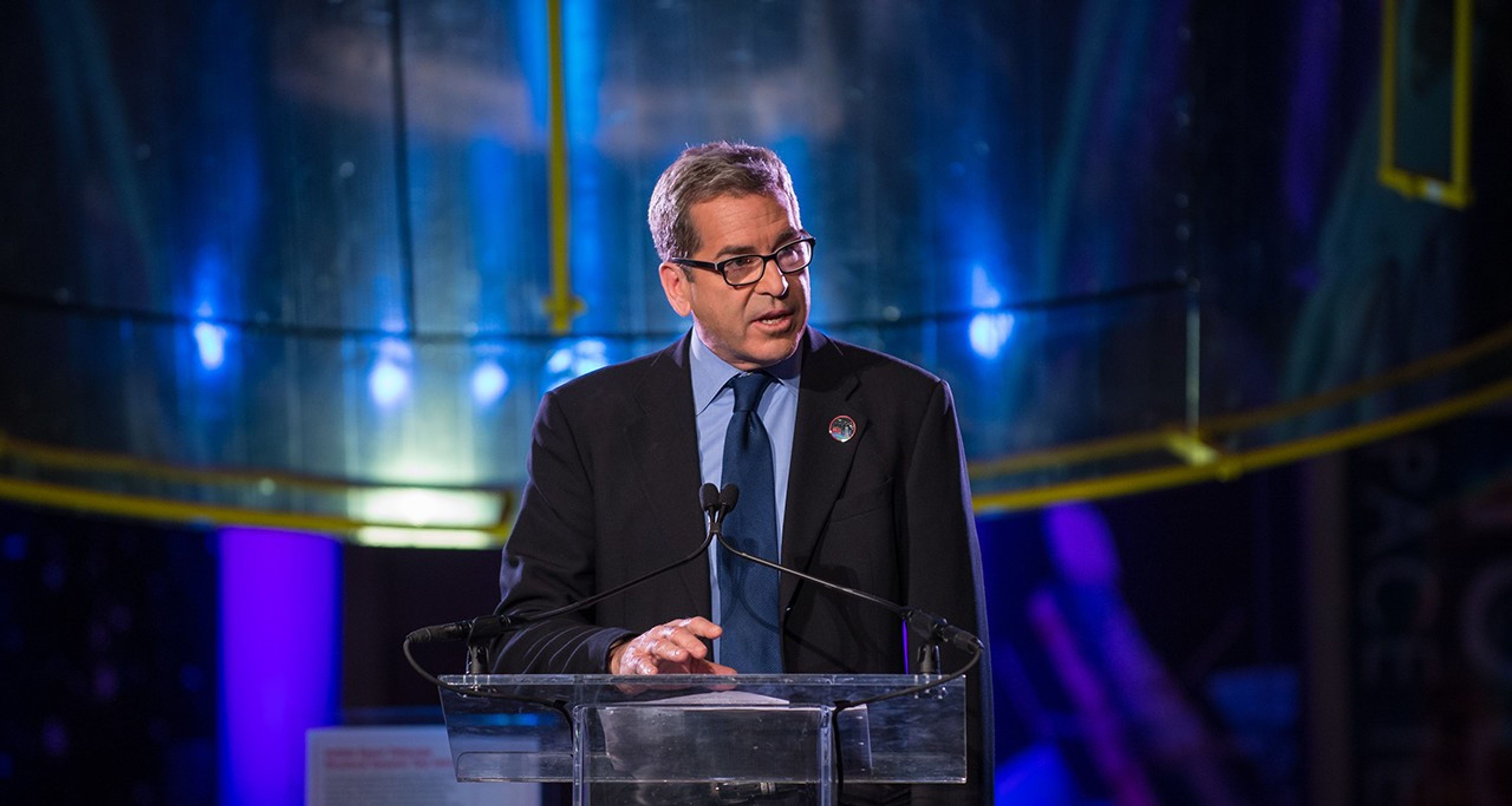 Miles O'Brien stands at the podium, addressing the audience.