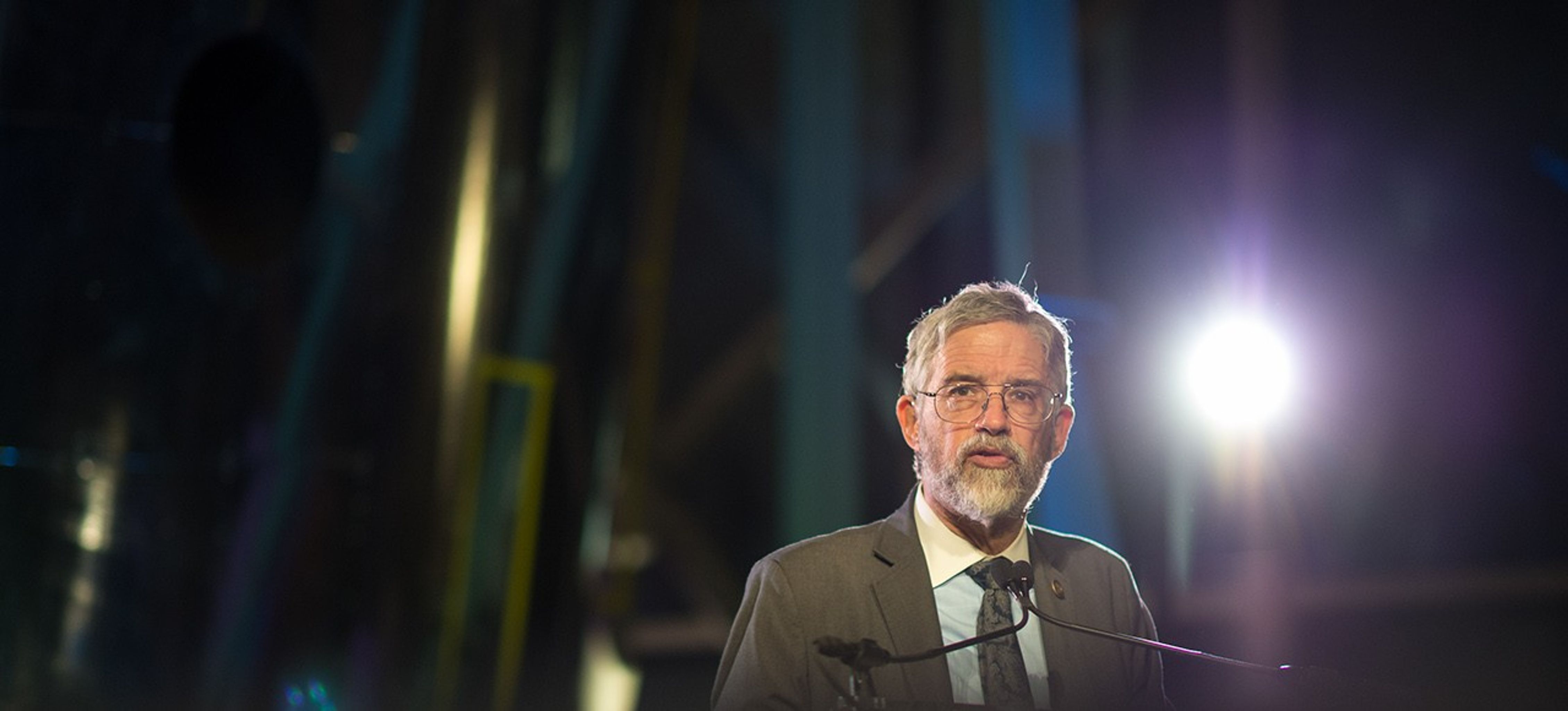 John Holdren stands at the podium, addressing the audience.