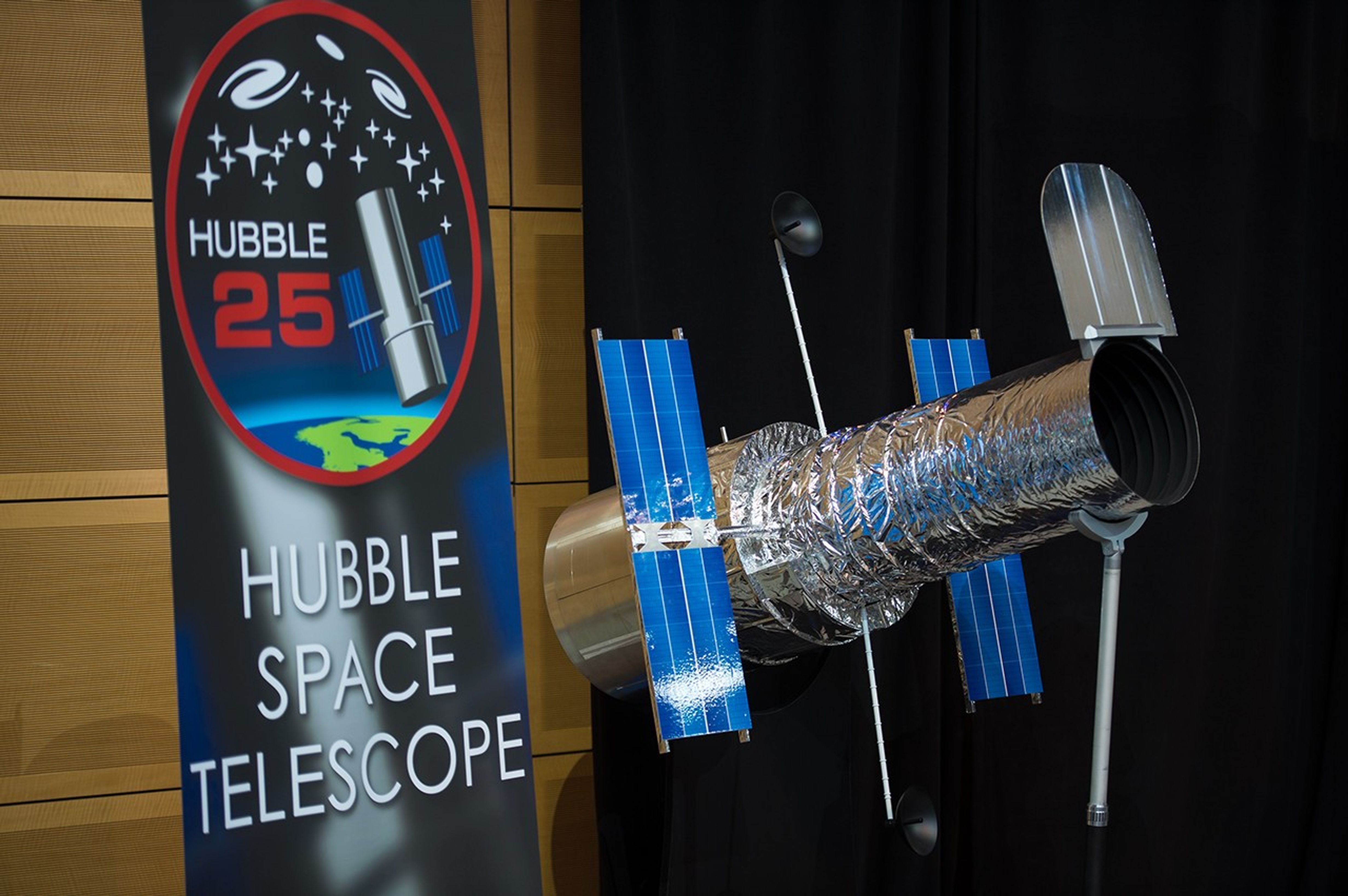 A scale model of Hubble is on display. To the left of it is a Hubble Space Telescope banner, with a logo for Hubble's 25th anniversary