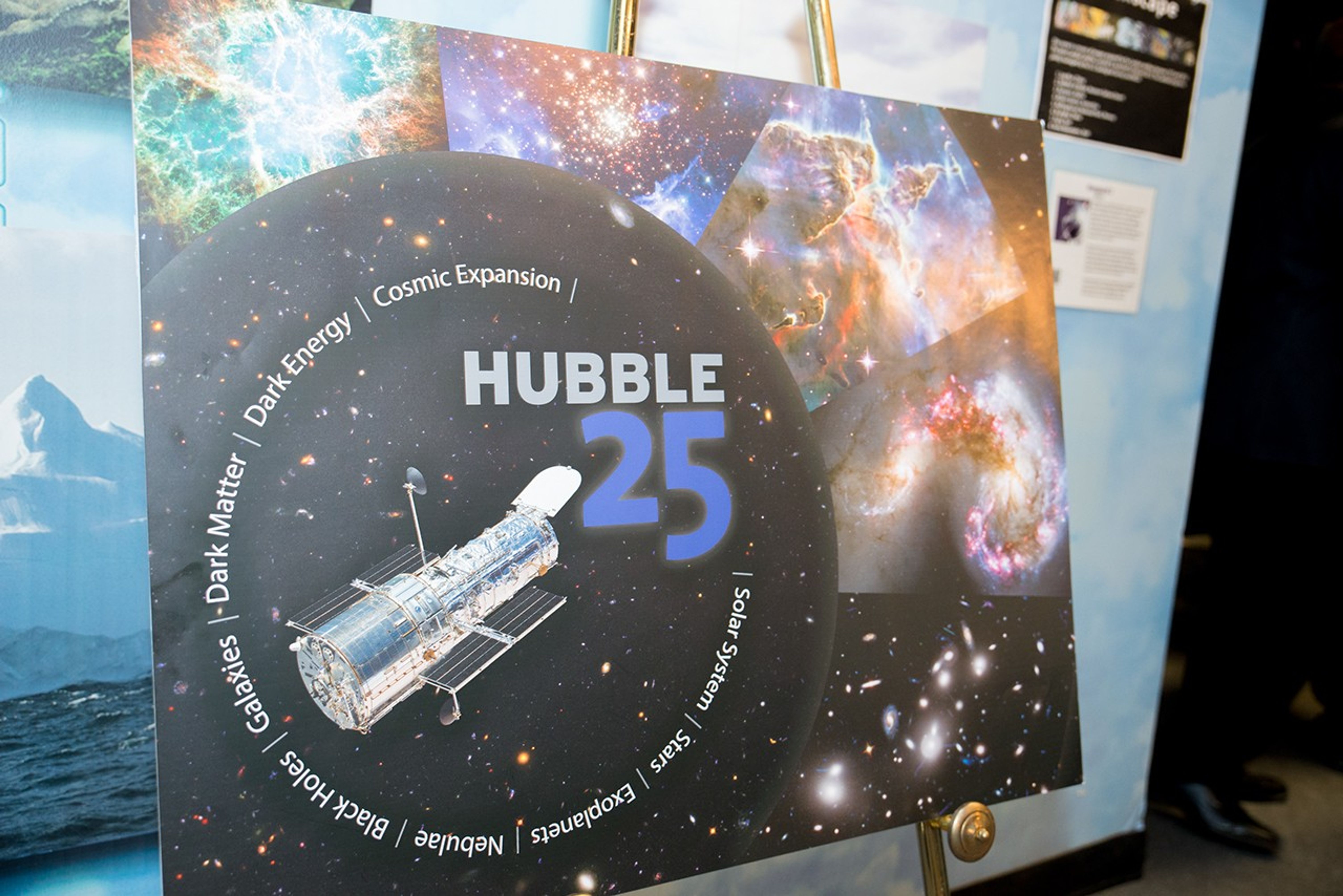 A poster for Hubble's 25th anniversary sits on a gold-colored easel.