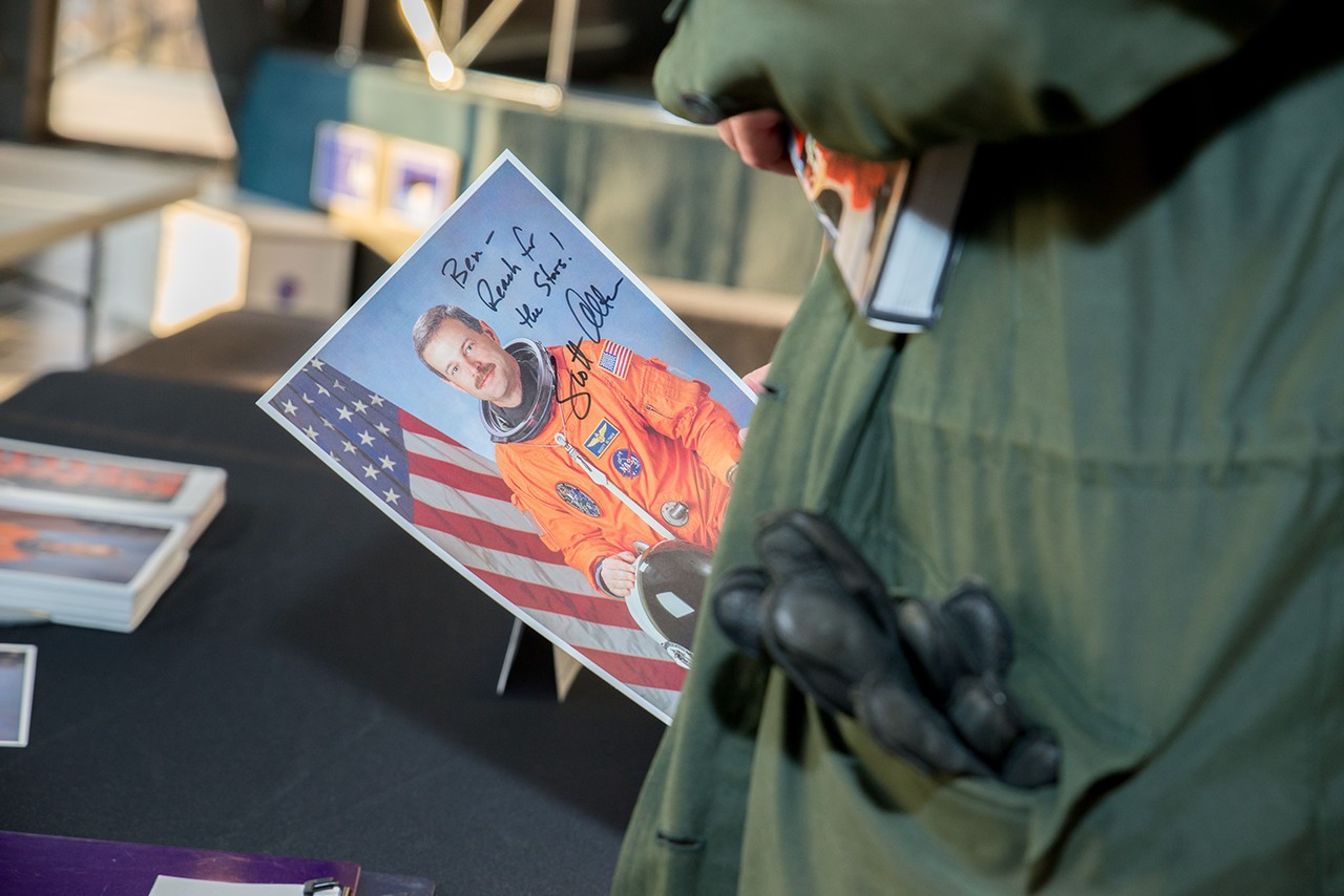 A visitor holds an astronaut image of Scott Altman that he's just signed.