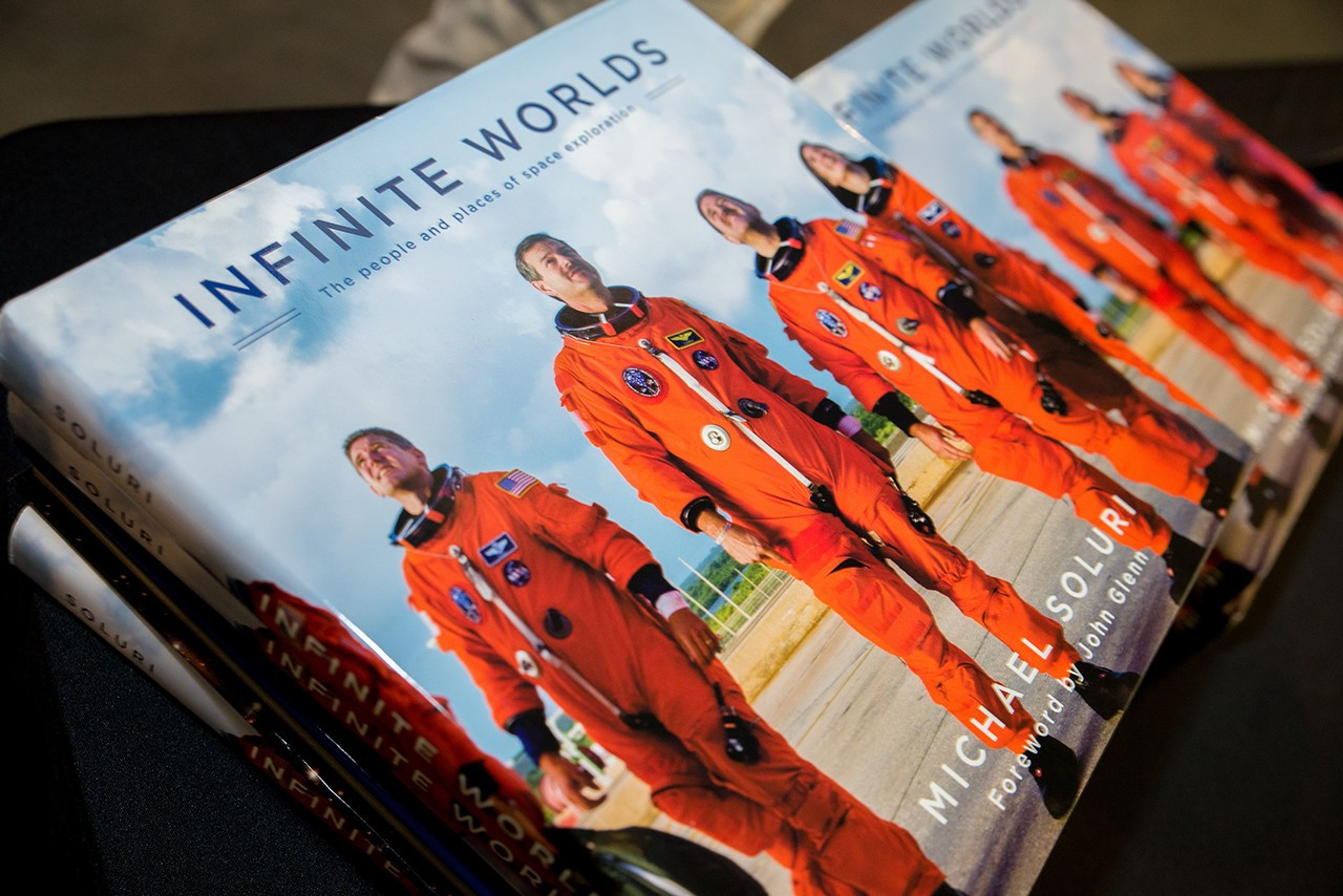 Several copies of Soluri's book, "Infinite Worlds" (which has a photo of several astronauts on the front) in two stacks.