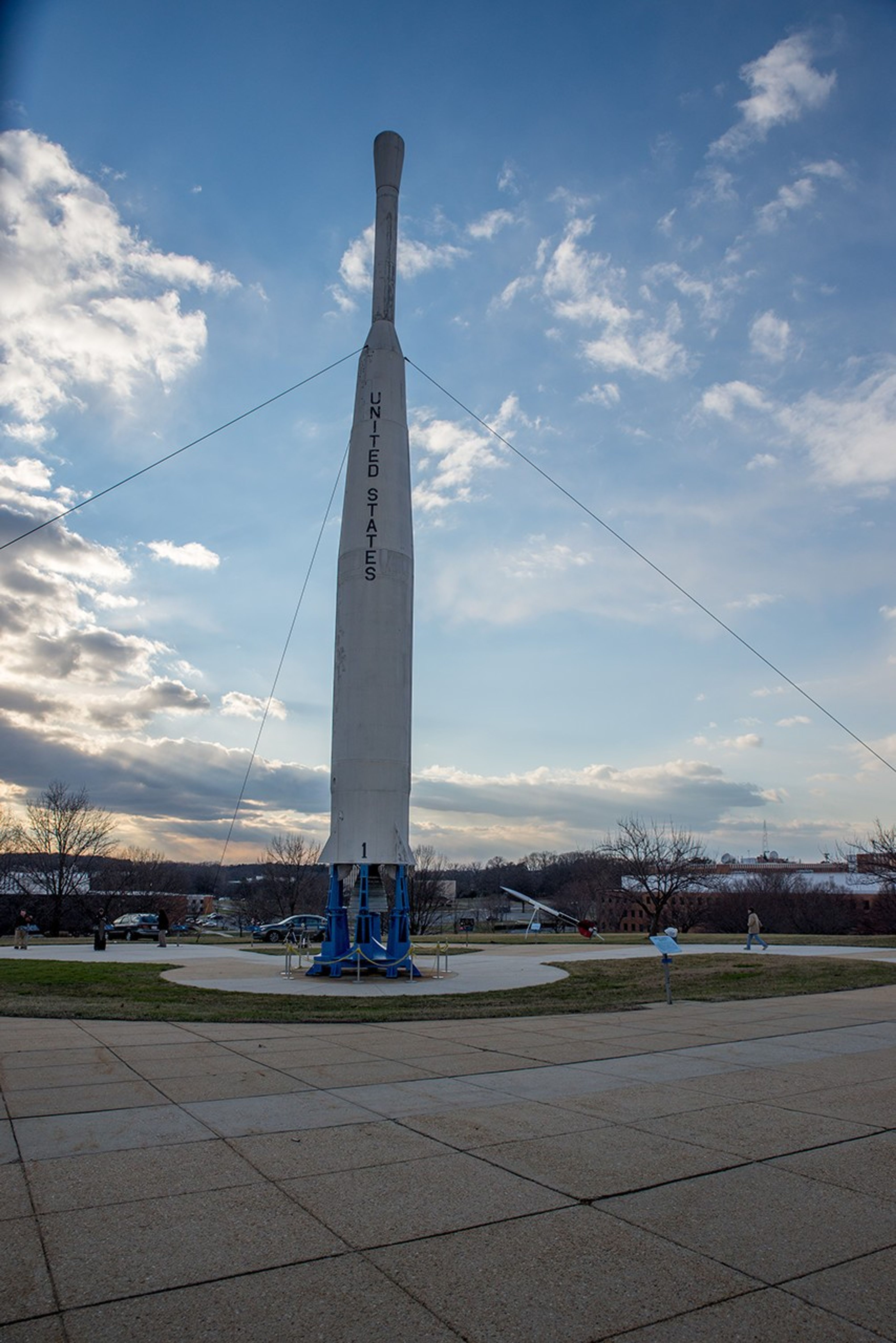 A white Delta-B rocket model with "United States" printed down the side. In the background is a partly cloudy sky at dusk.