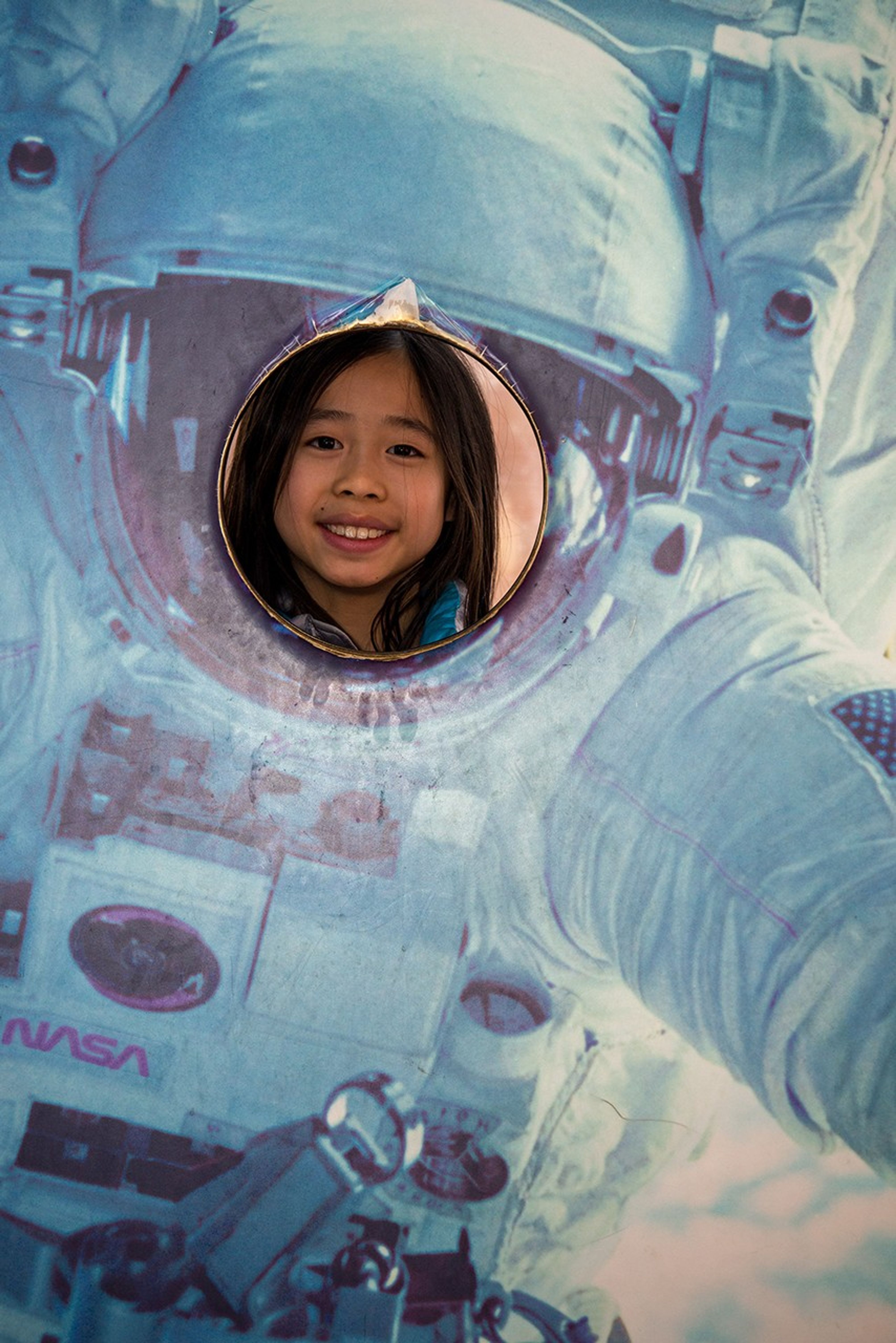 A model of an astronaut has an open circle gap over the faceplate where people can take photo-ops. A young girl does so here.