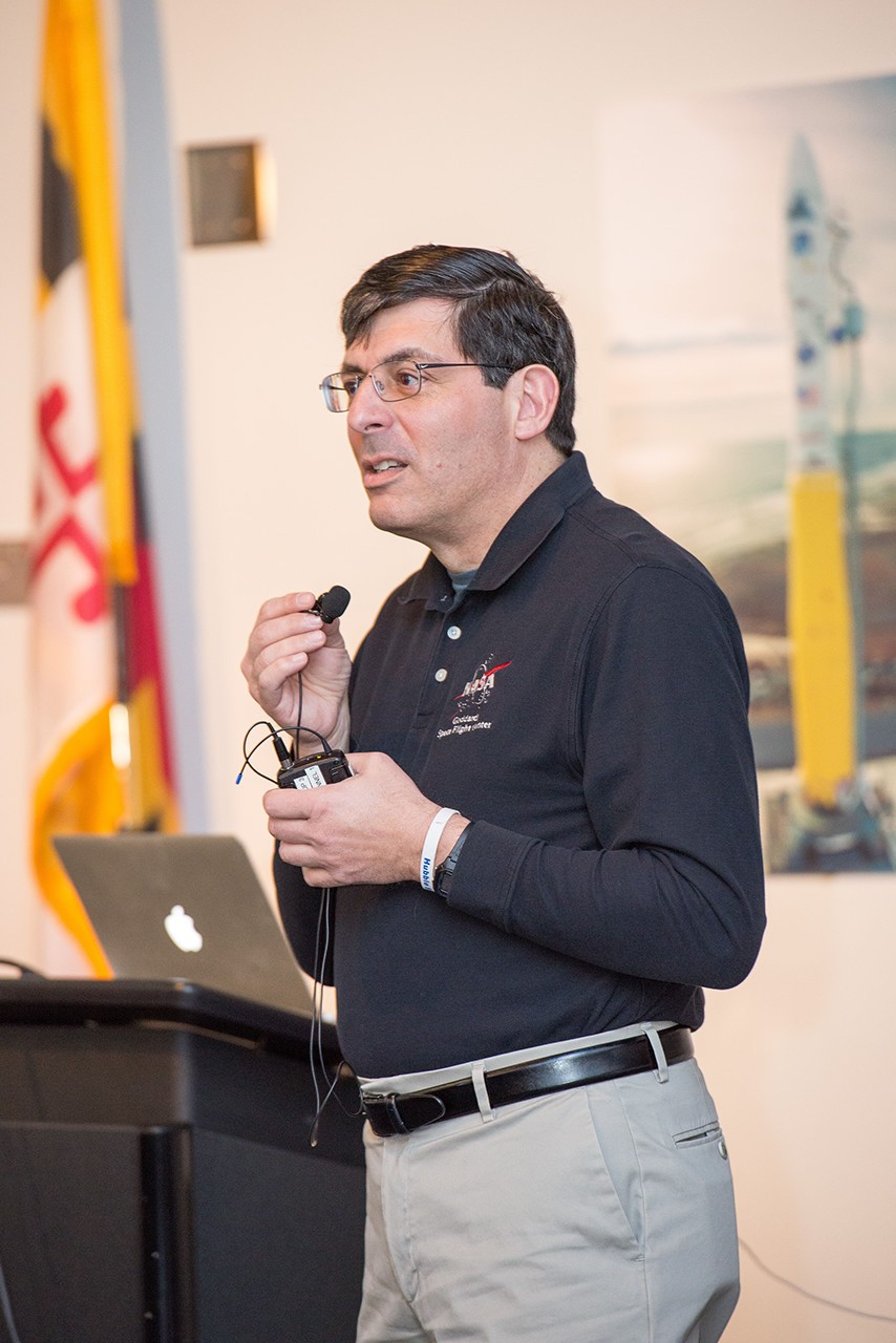 Christopher Scolese stands in front of a podium and speaks into a handheld mic.
