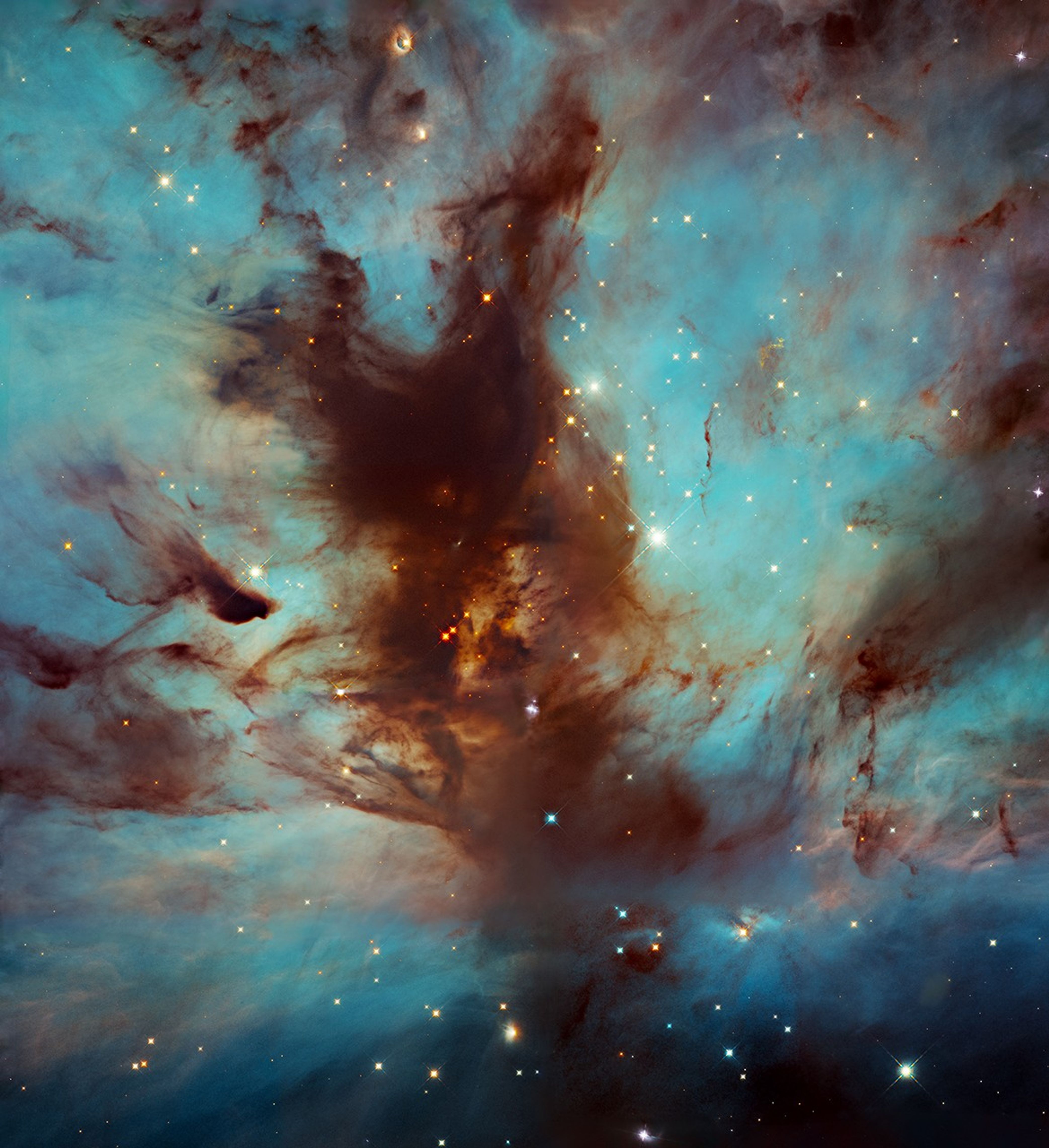 Dark nebula looking like a flame rising through the center of the image against a turquoise and blue glowing nebula, stars dotted throughout.