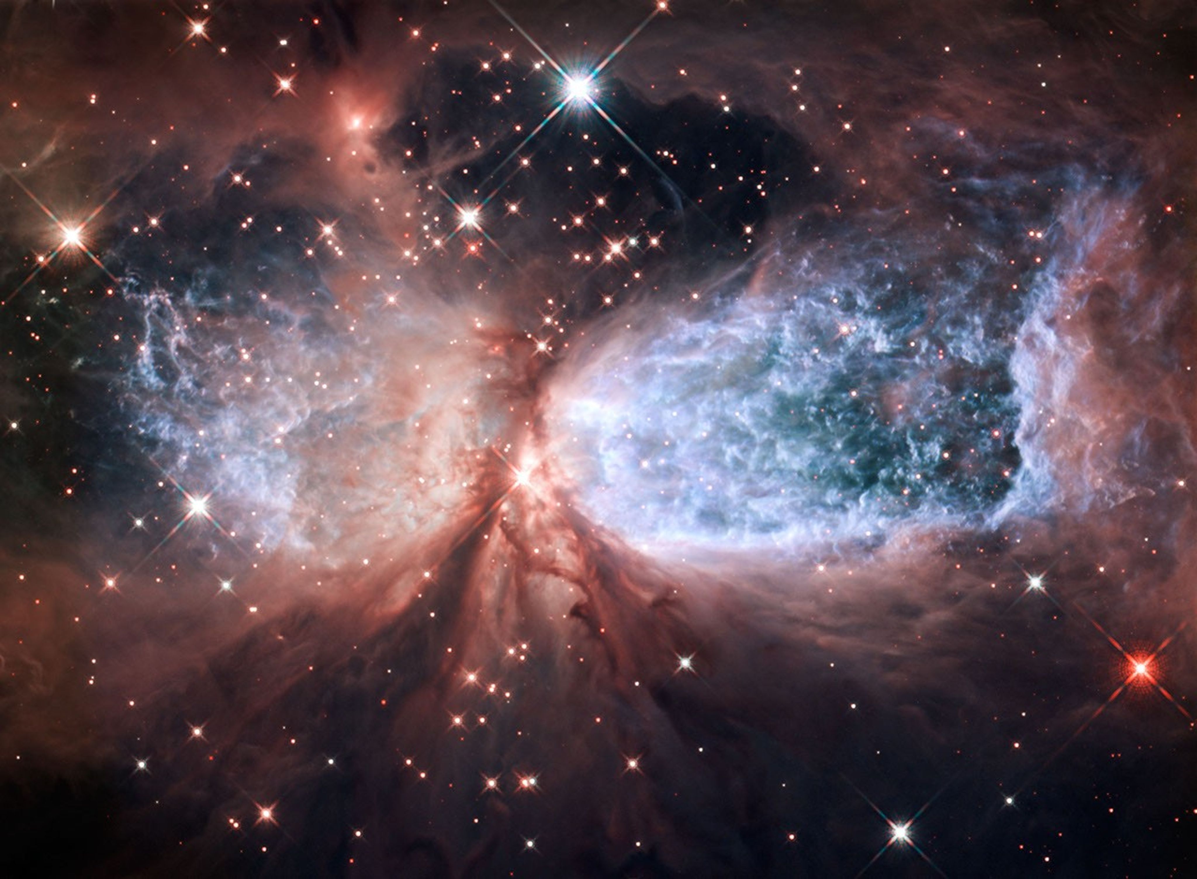 Two blue lobes of hot gas, shaped like wings, surrounded by reddish-pink gas and dust.