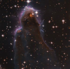 Whisp-like, purple-hued view of star-forming region against black backdrop of space.
