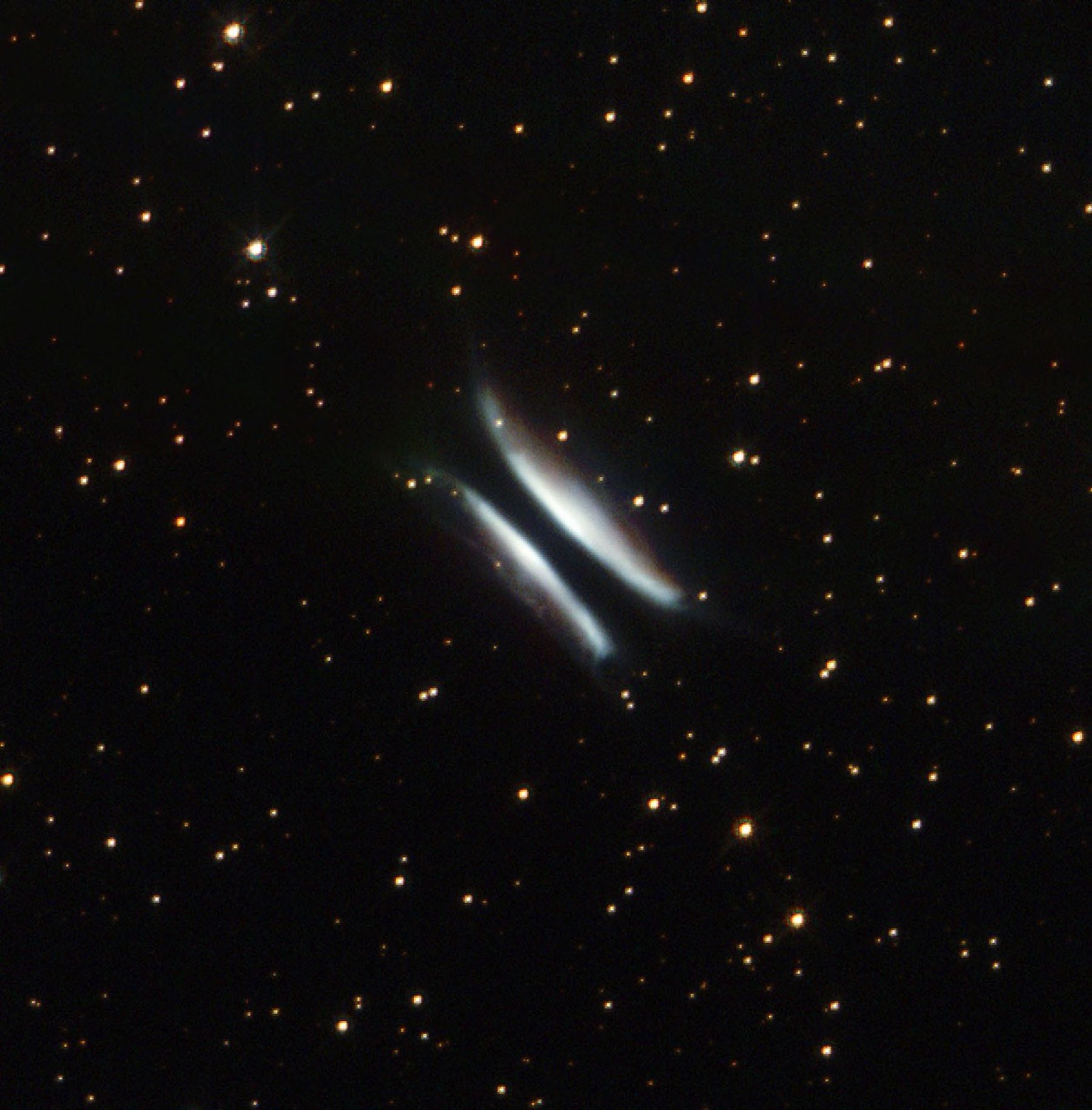 Two white, hyperbolic/bow-shaped arcs of gas and dust with what appears to be a black streak passing through the middle, set against a black backdrop with hundreds of stars.
