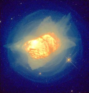 Bright yellow-orange cloud of dust and gas forming a glob in the center with thin light-yellow gas surrounding it, while the outer edges are blue.