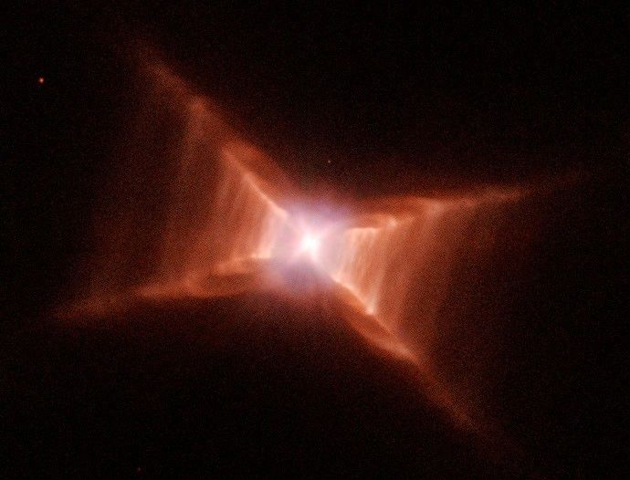 A glowing star at the center of what looks like a red X. Closer to the center, red-orange rectangular clouds of gas and dust are thicker., thinning out before reaching the "ends" of the X.