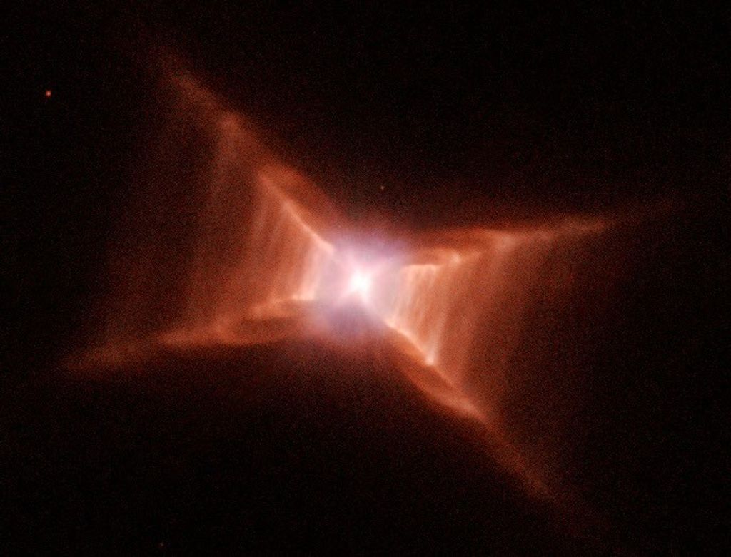A glowing star at the center of what looks like a red X. Closer to the center, red-orange rectangular clouds of gas and dust are thicker., thinning out before reaching the "ends" of the X.