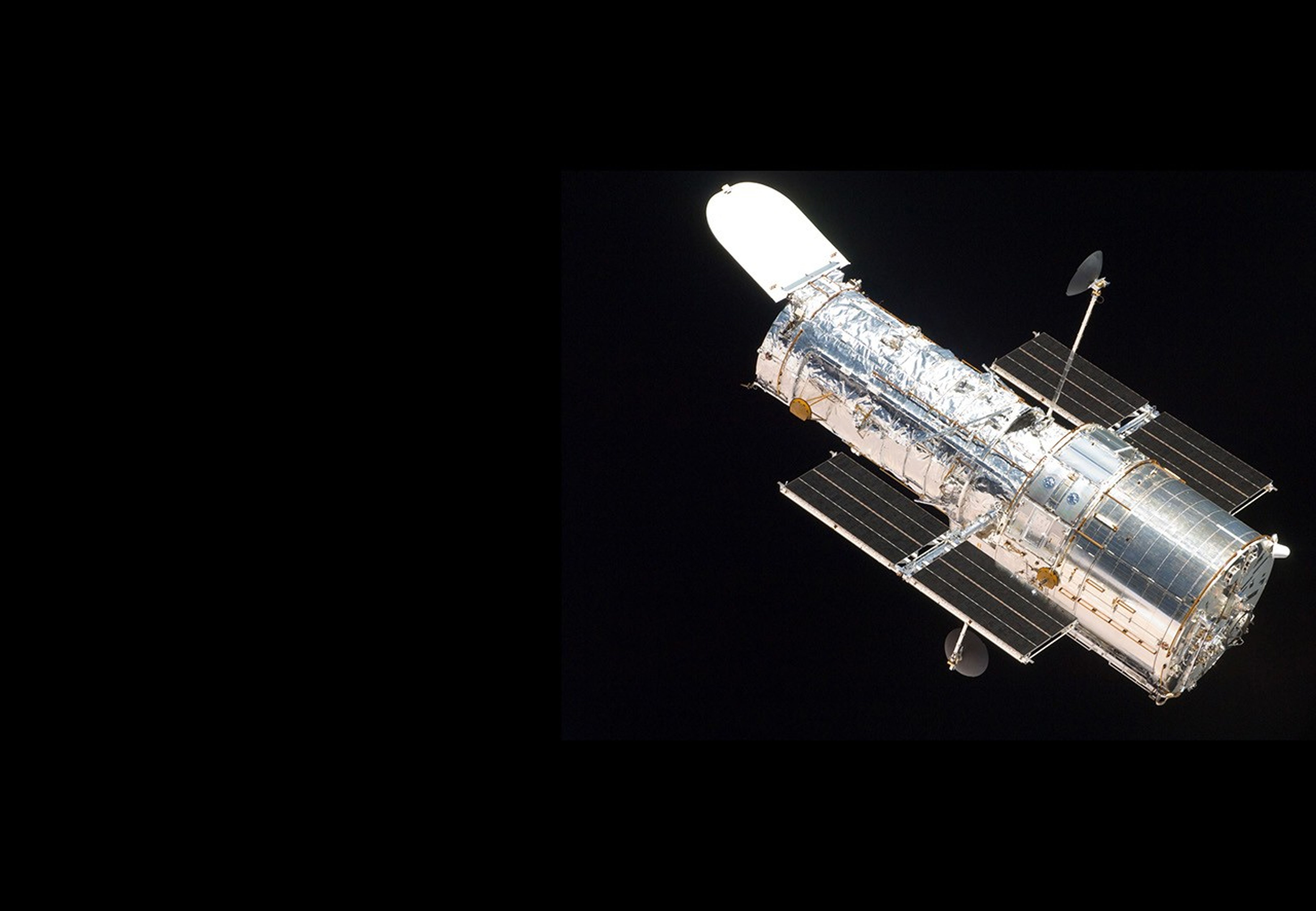 Hubble in orbit on the right side of the image, against the blackness of space. Taken during Hubble's fifth servicing mission, STS-125.