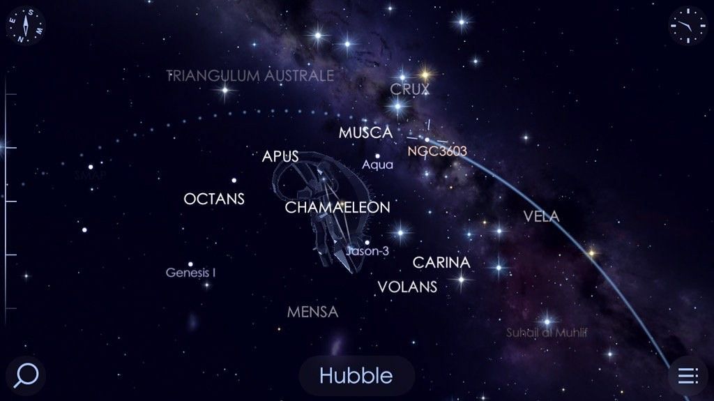 A screenshot from a stargazing app, showing several constellation names against a backdrop of a starry sky and the disk of the Milky Way.  Near the center is a dot with crosshairs over it to show where Hubble currently is; its path across the sky is represented by a blue arc extending from the lower right (showing where it came from) and a dotted arc extended to the left (where it's going).