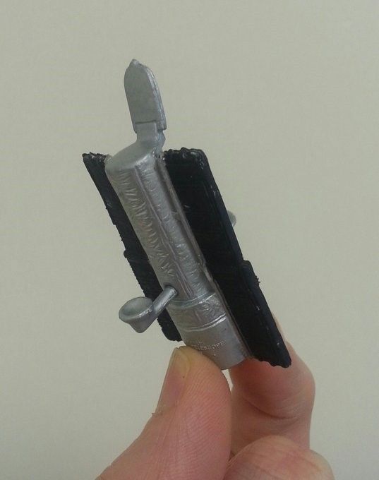 A person holds a very small, simple model of Hubble between their fingertips.