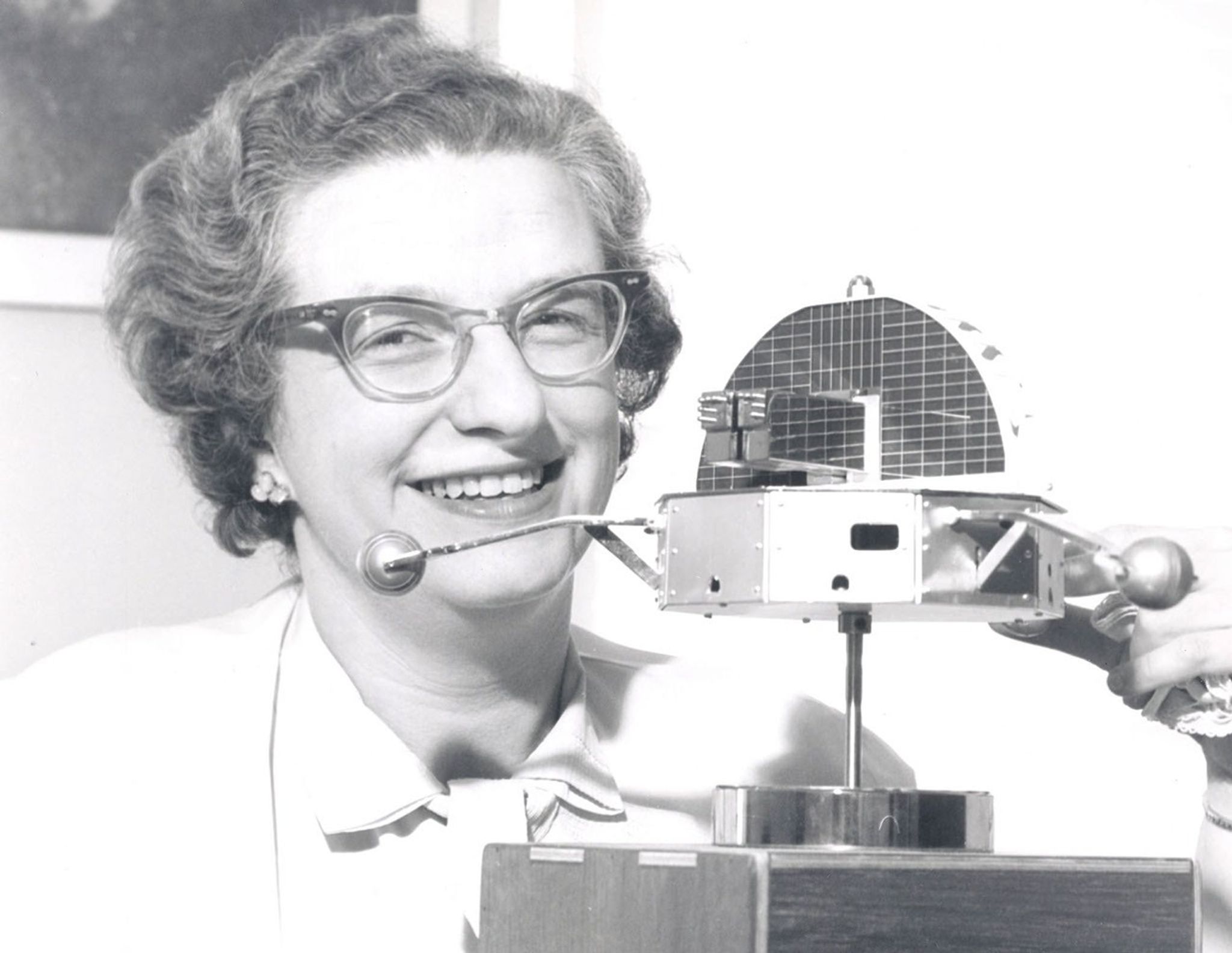 Dr. Nancy Grace Roman poses with a model of the Orbiting Solar Observatory (OSO).