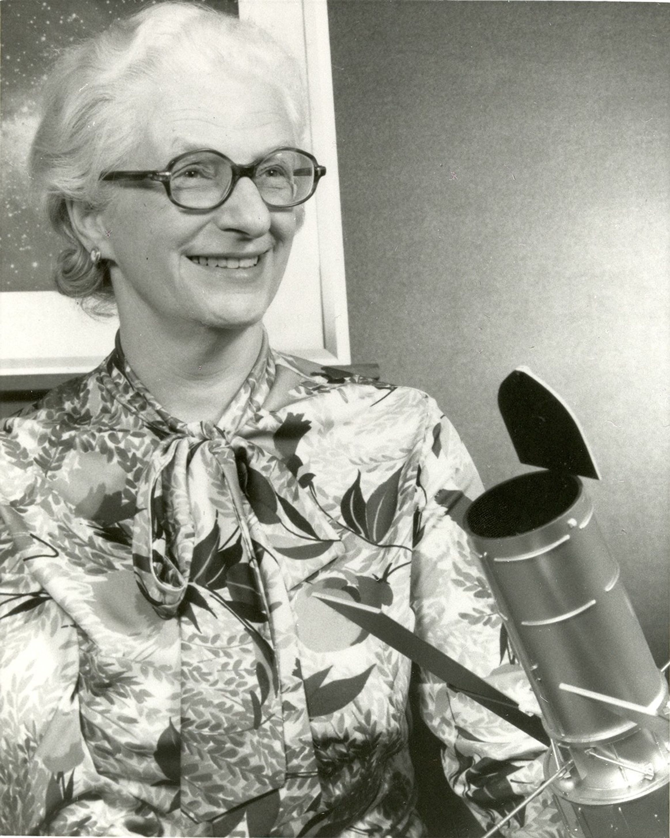 Dr. Nancy Grace Roman poses with a model of the Hubble Space Telescope.
