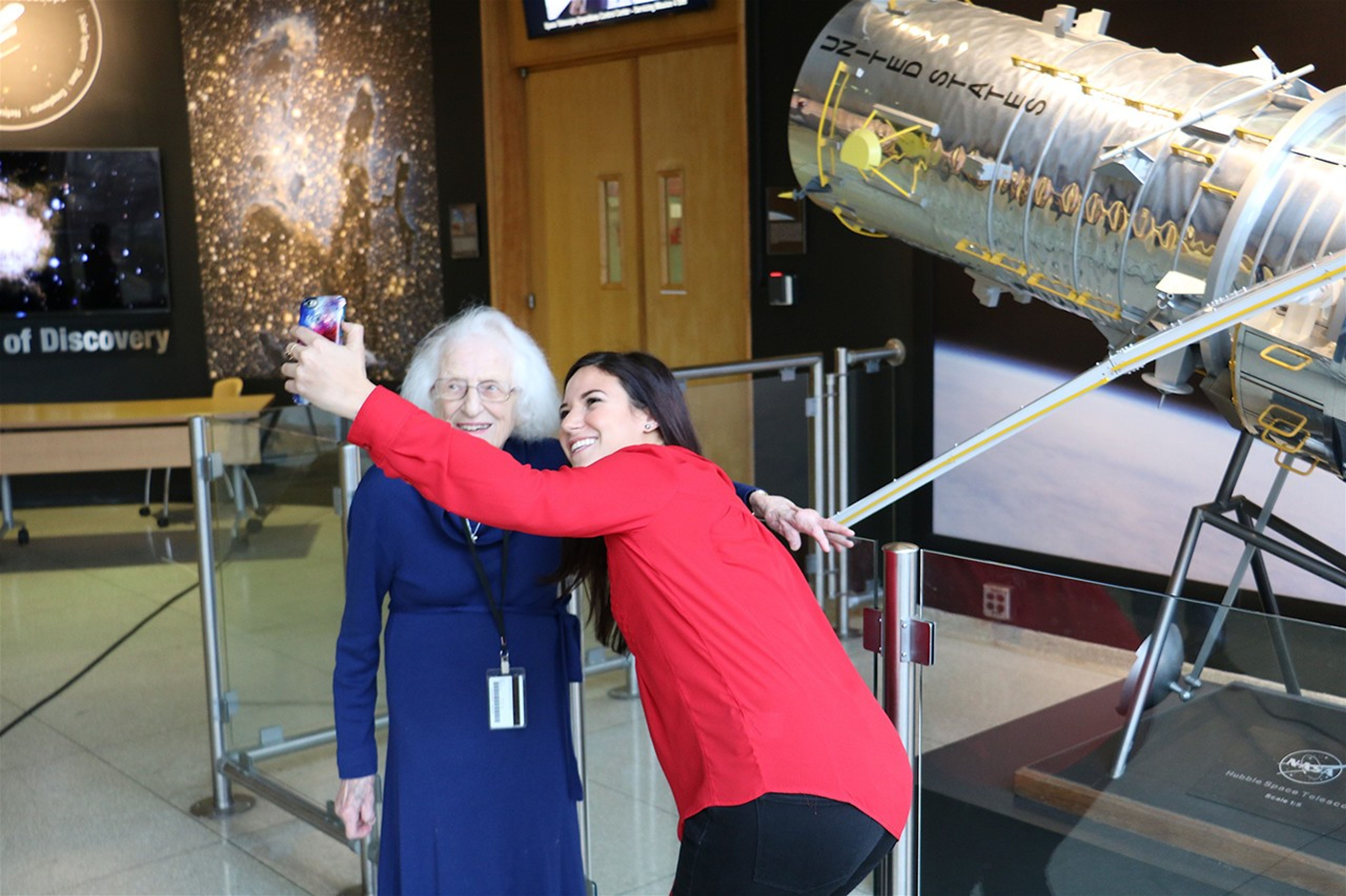 Erin Kisliuk takes a selfie with Nancy Grace Roman in front of the Hubble model in GSFC Building 3.