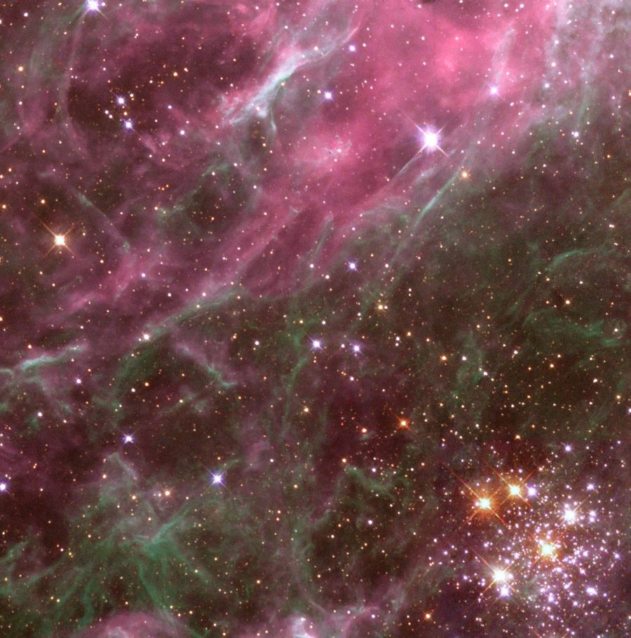 Pinkish sheets and filaments, seen in the upper left portion frame a cluster of brilliant, massive stars in the lower right.
