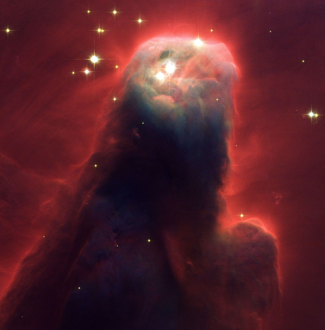 A wide, dark pillar surrounded by wispy red tendrils extends from lower left to upper right across most of the frame. The cone-shaped pillar narrows gradually to a smooth, rounded top.