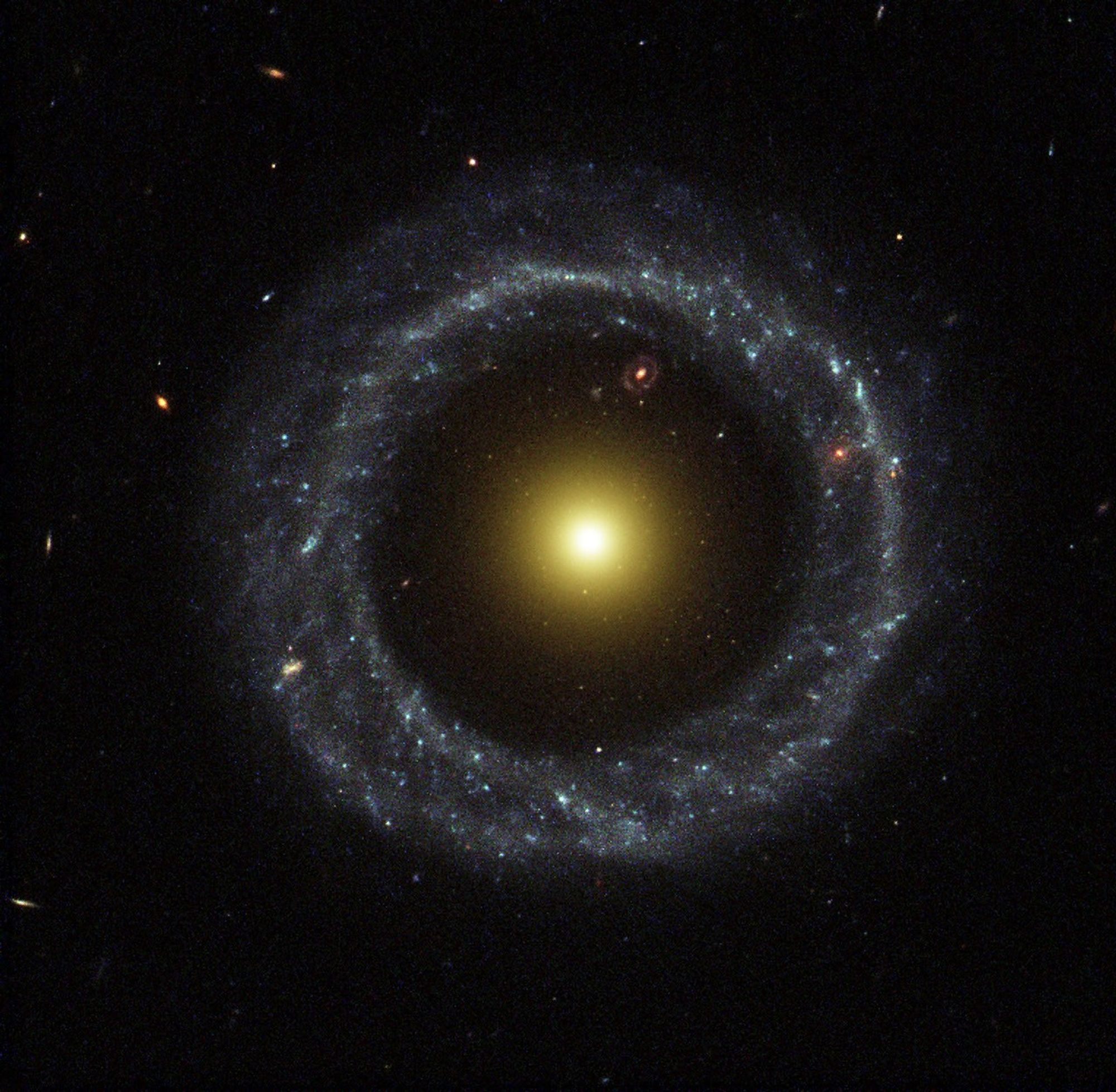 A large ring of circular blue stars surrounds a bright, large yellow nucleus, with a large gap between the ring and the nucleus.