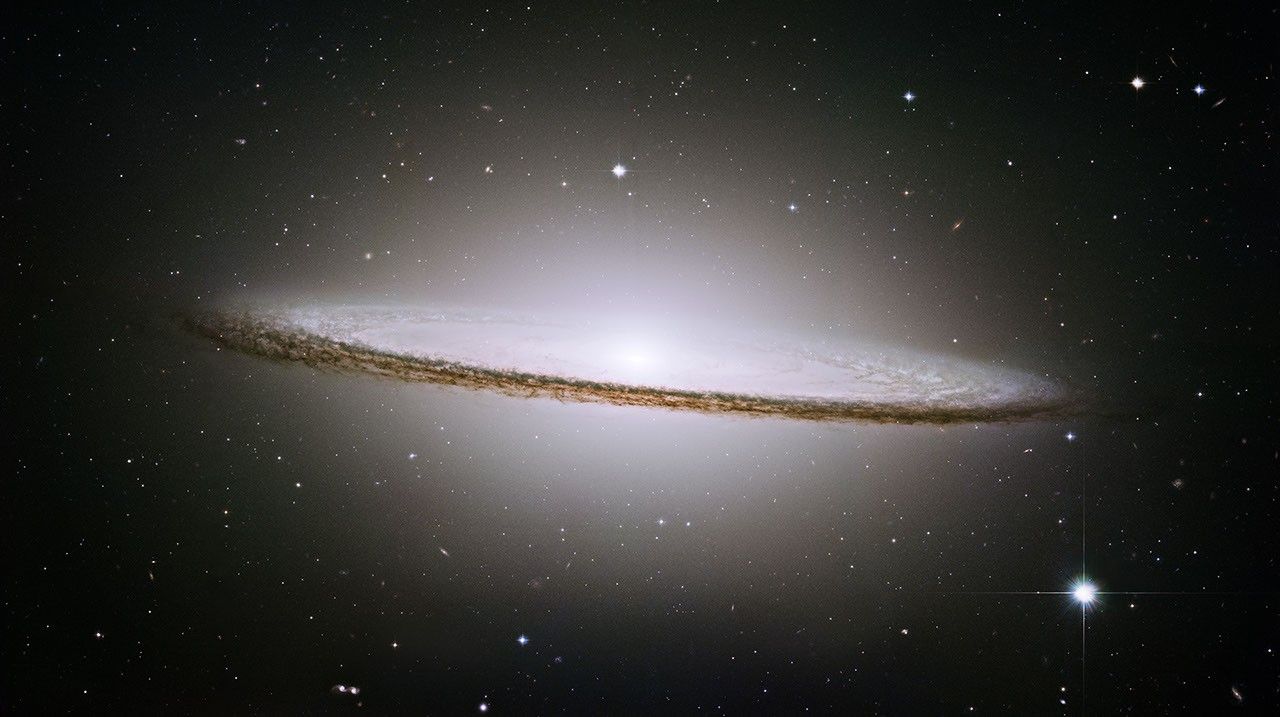 A very oblong, pale white disk with a bright center extends from left to right on a black background.