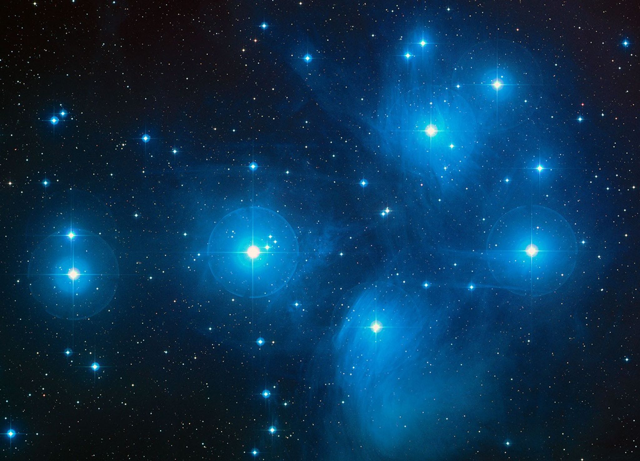 Members of the Pleiades shine in blue.