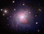 A galaxy with a white center surrounded by pink lobes above and below it. Outside the pink lobes is a violet shell that surrounds the galaxy. From the center of the galaxy are stringy filaments of red gas.