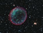 Supernova remnant resembling a bubble. Its exterior is tinged with red, while its interior has blue-green blotches.