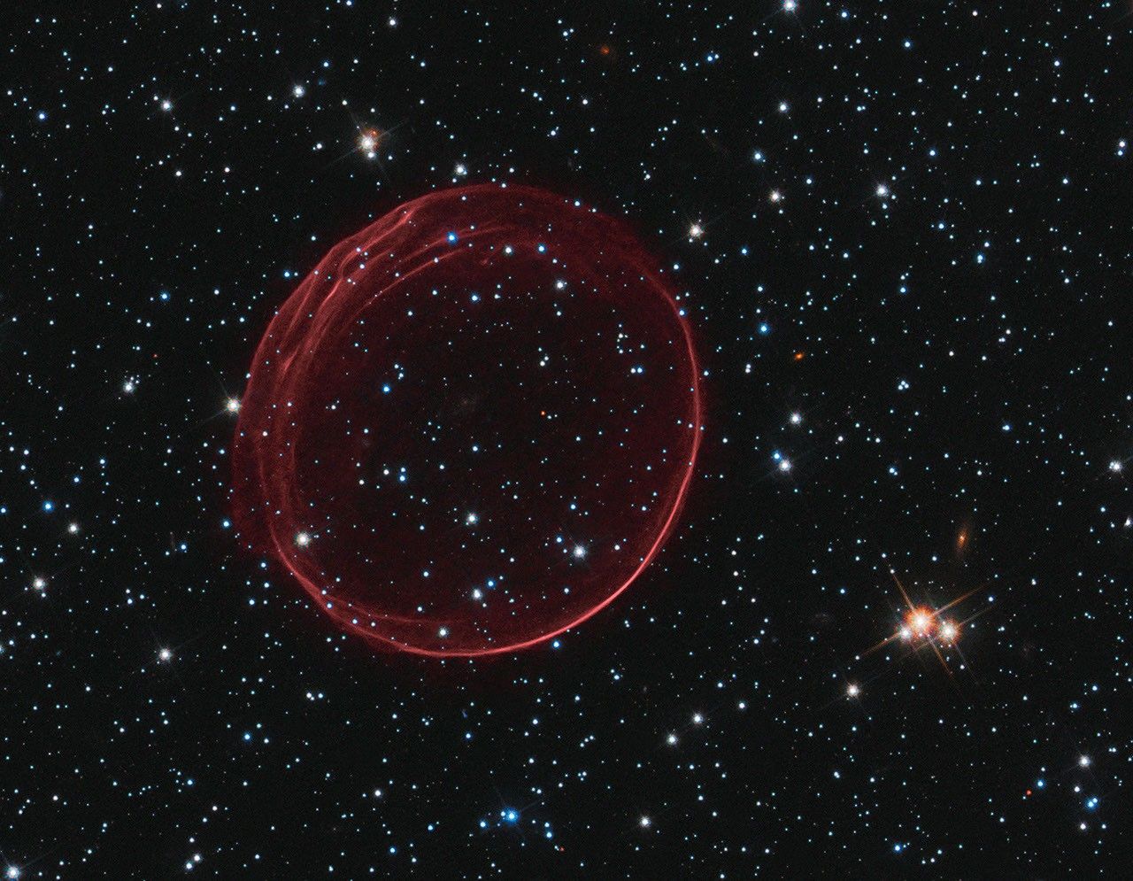Supernova remnant resembling a bubble tinged with red.