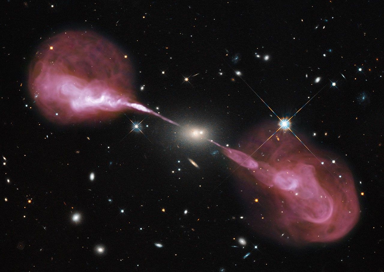 Small yellow elliptical galaxy with enormous pink jets projecting out in opposite directions, far into space.