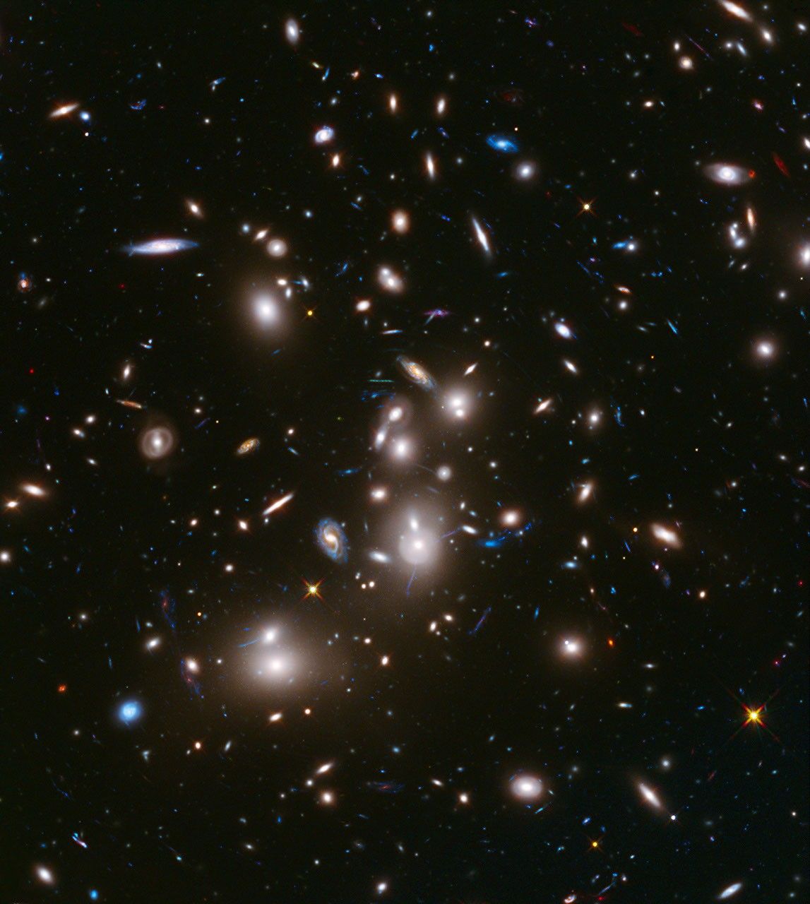 Hundreds of galaxies in a diverse array of shapes and colors are scattered across the dark background of space.